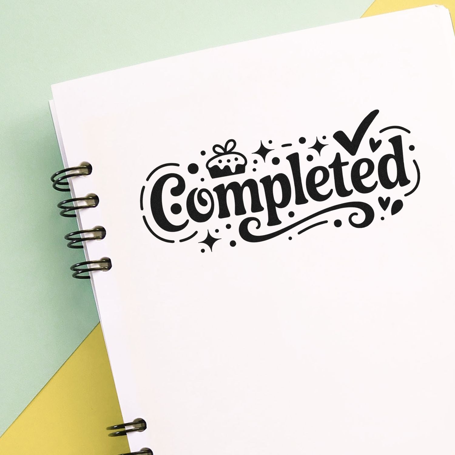 Decorative black Completed stamp/seal on white spiral notebook page with pastel green and yellow background.