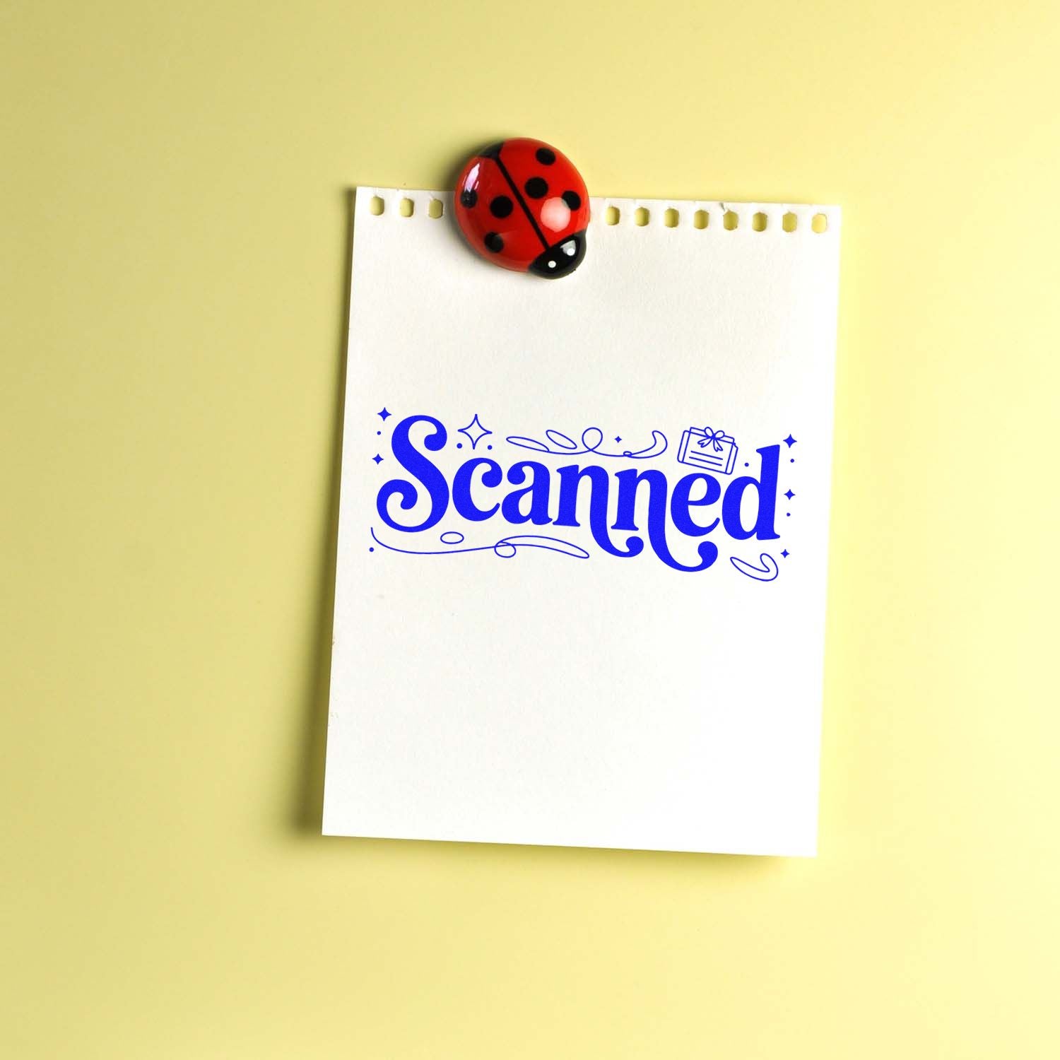 Blue Scanned stamp on white notepad paper with a red ladybug seal, set against a pale yellow background.