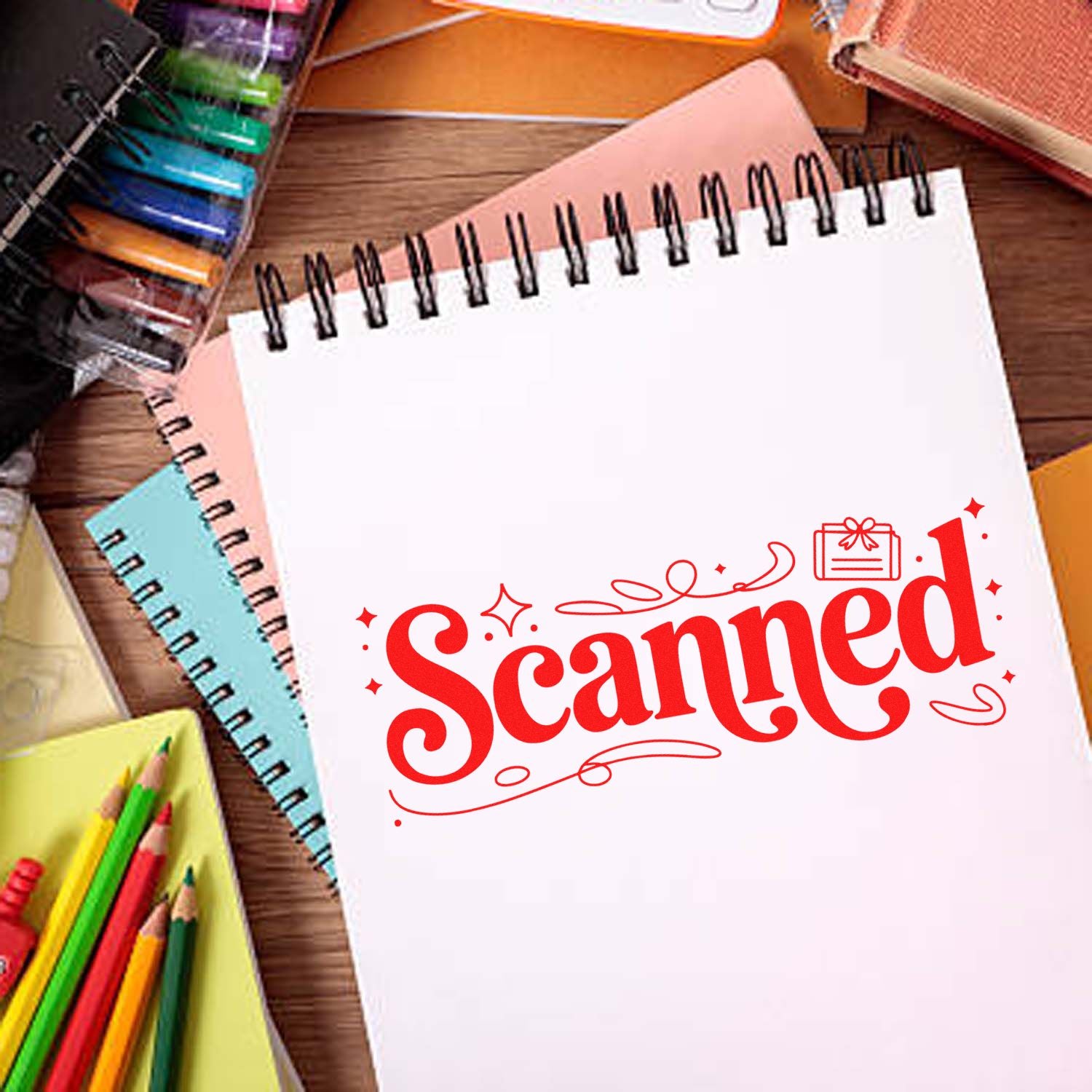 Red Scanned stamp seal on a white spiral notebook, with colorful notebooks and pencils on a wooden desk.