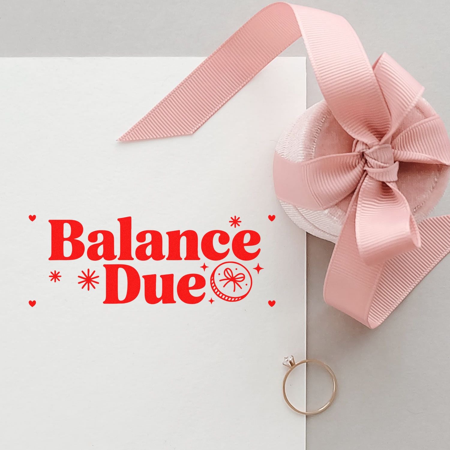Red Balance Due stamp on white paper with pink grosgrain ribbon bow and blush seal embellishment.
