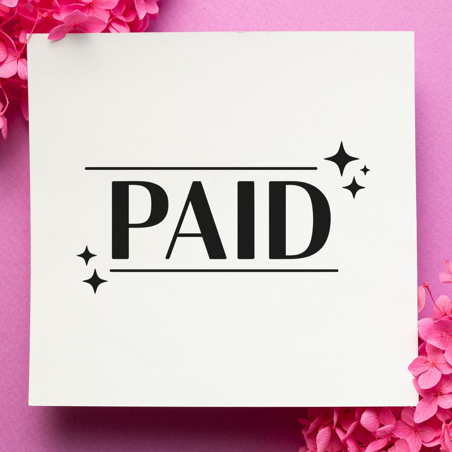 Black PAID stamp and seal with sparkle accents on a white card, framed by bright pink flowers on a soft pink background.