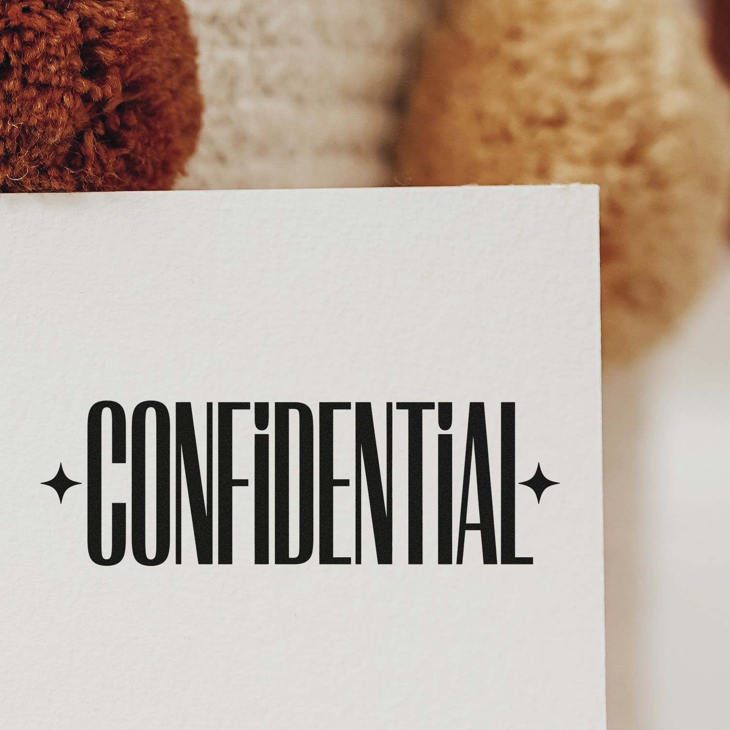 White confidential stamp and seal card with bold black lettering and star icons against a warm brown background.