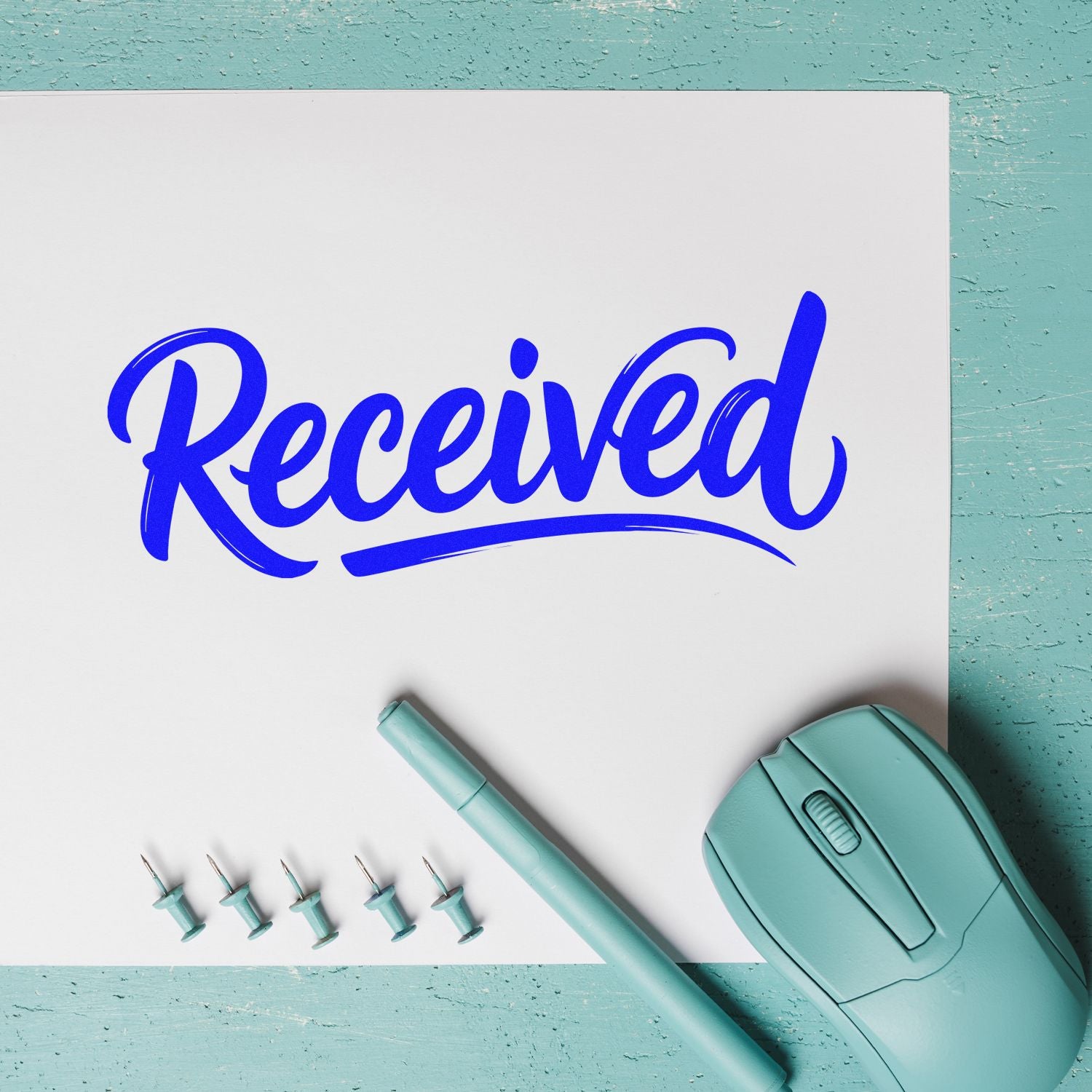 Blue "Received" custom stamp on white card with mint embossing seal, pen, and pins on aqua background.