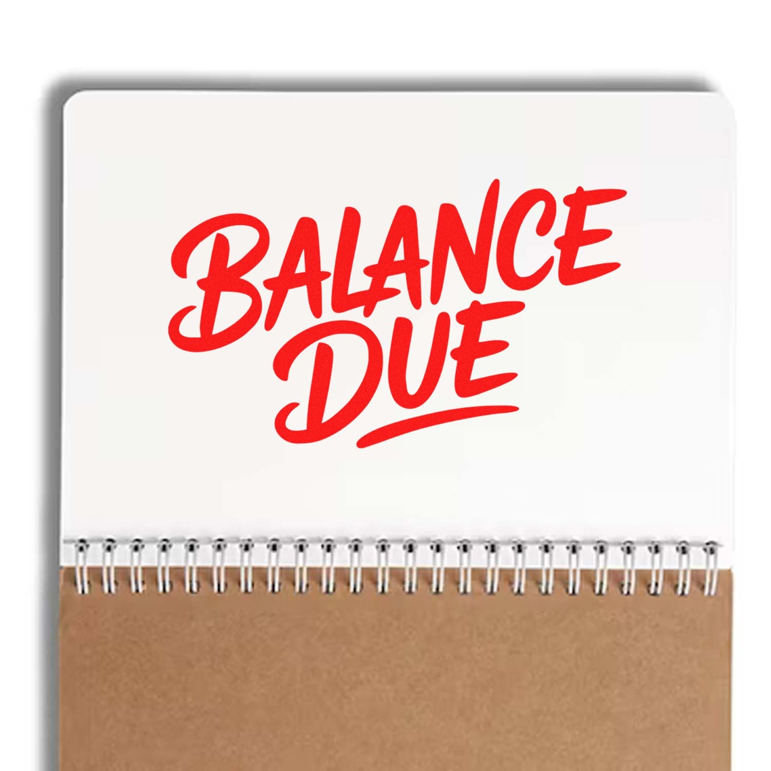Red Balance Due stamp seal on white notebook with brown kraft cover and spiral binding