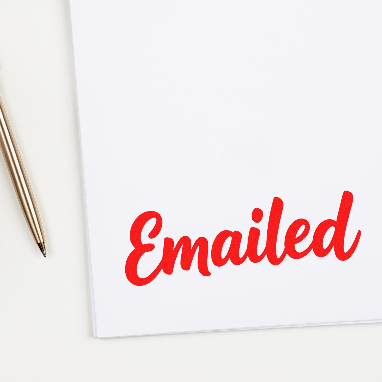Red "Emailed" rubber stamp on white paper beside a gold pen