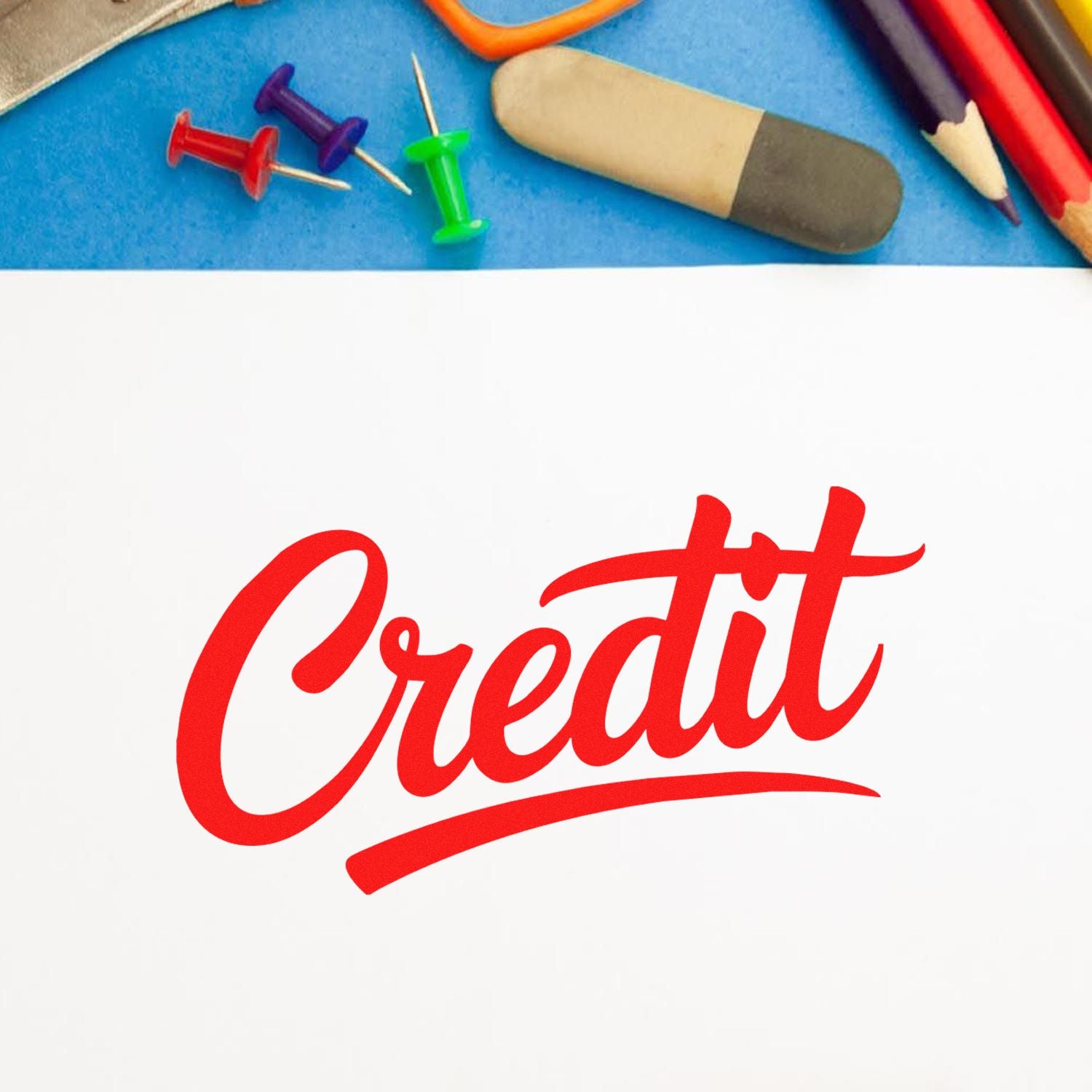 Red Credit stamp and seal on white paper, with blue background, colorful push pins, eraser, and pencils.