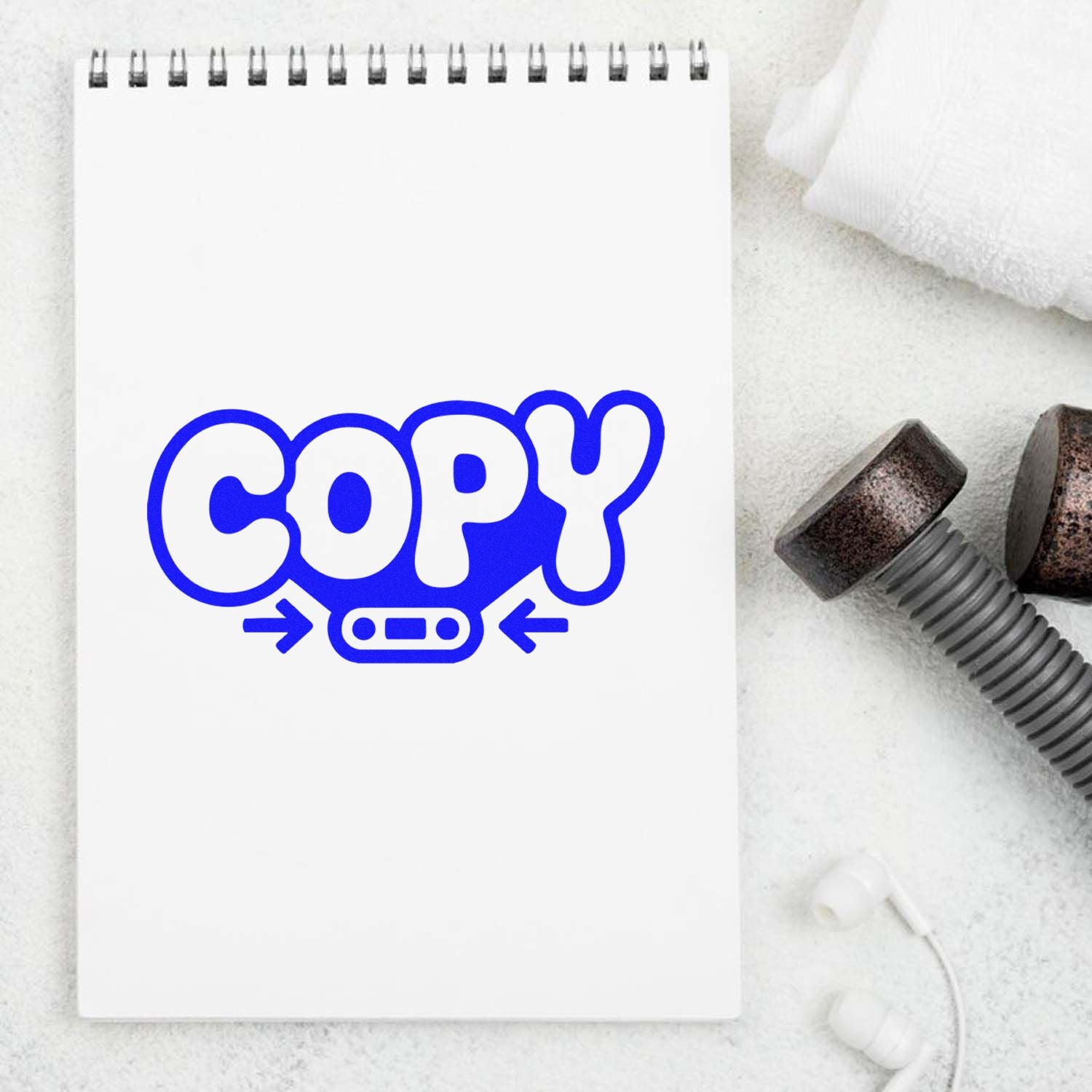 Blue COPY stamp seal on a white spiral notepad, with black stamp handles on a light textured background.