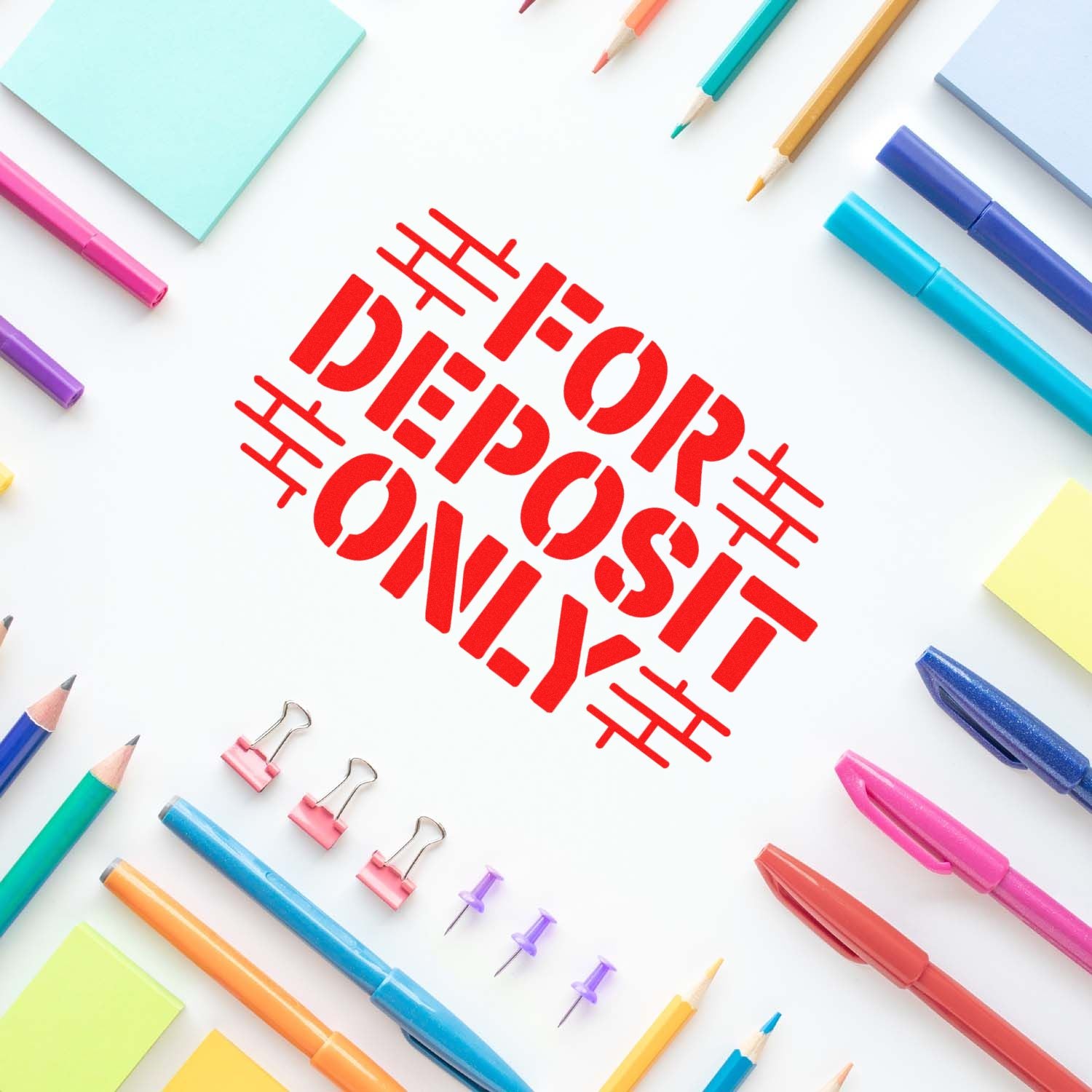 Red FOR DEPOSIT ONLY bank stamp and seal, surrounded by colorful pens, pencils, binder clips, and sticky notes.