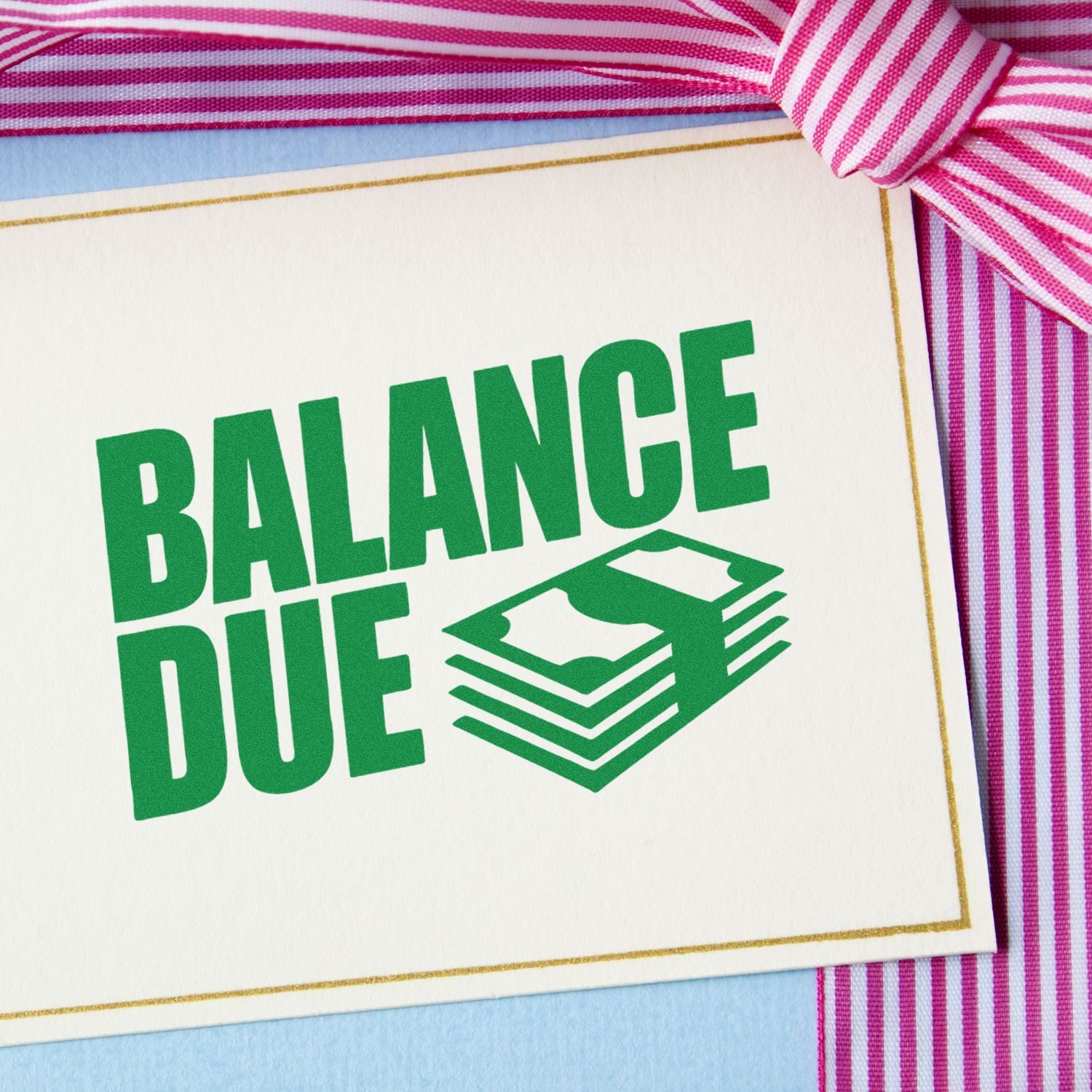 Green Balance Due stamp and seal with stacked bill icon, on white card with gold border and pink striped ribbon.