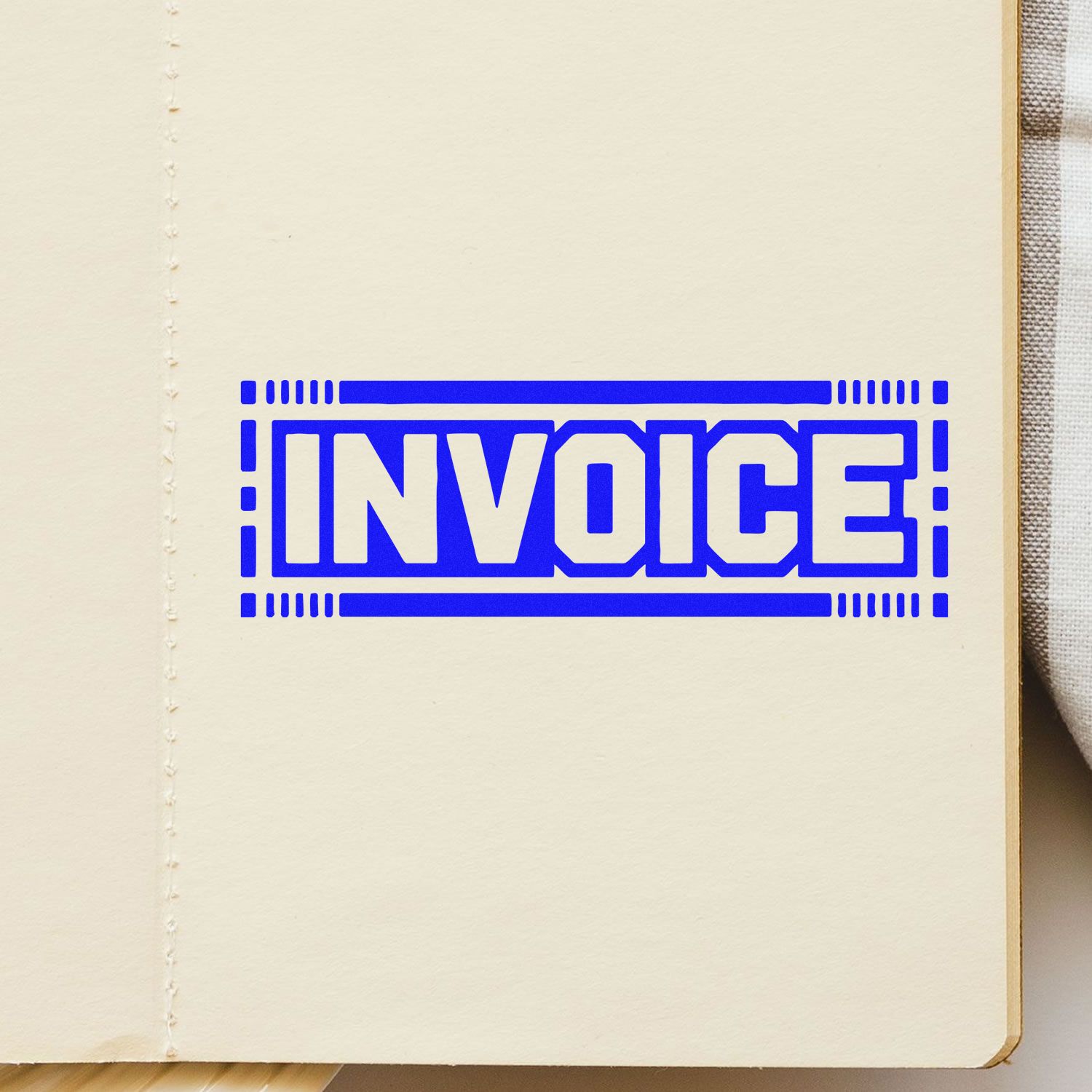 Blue INVOICE stamp seal in bold blue with decorative border on a cream paper page.