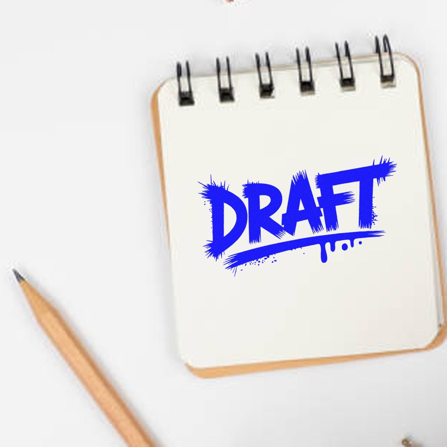 Blue DRAFT stamp on white spiral notepad with pencil, showing stamp and seal product design.
