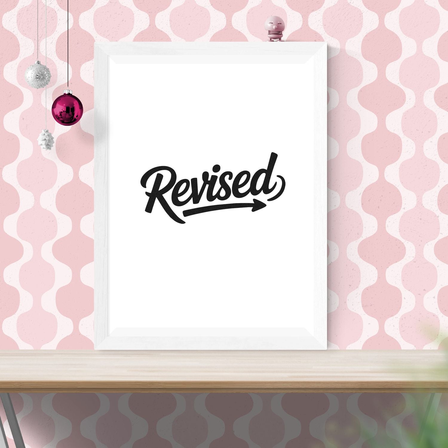 Revised self-inking stamp design on a white framed plaque, against a pink patterned background with hanging ornaments.