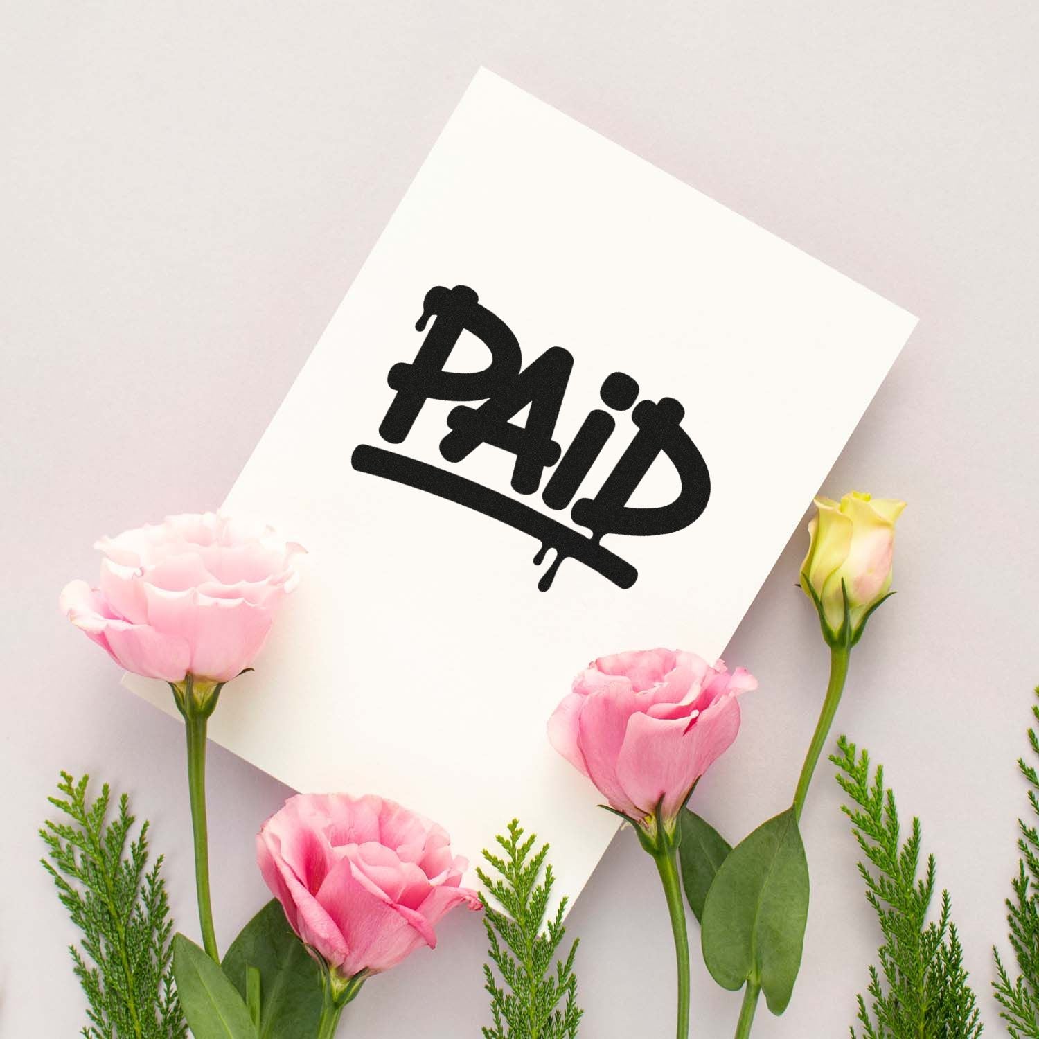 White card with bold black Paid stamp seal, surrounded by pink flowers and green sprigs on a pale background.