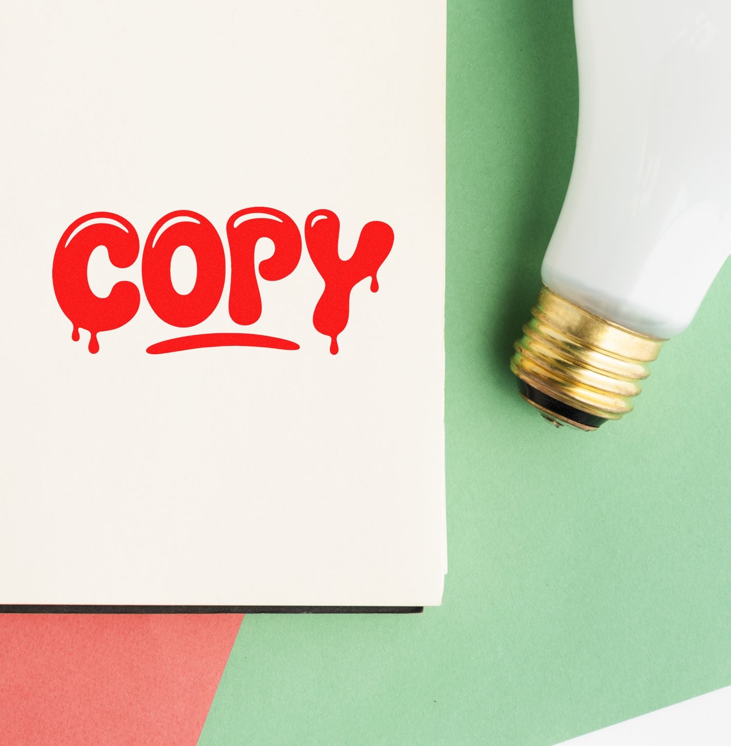Red COPY seal on white paper beside white-and-gold stamp tool on green background.
