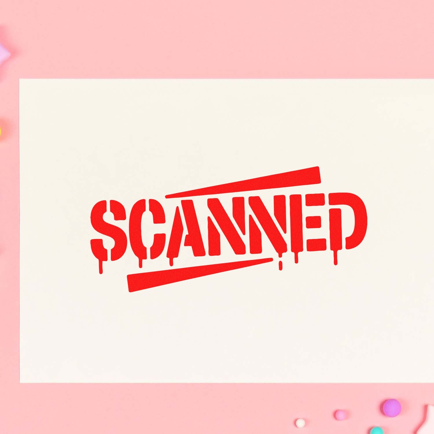 Red SCANNED rubber stamp with dripping letters on cream paper, set against a soft pink background.