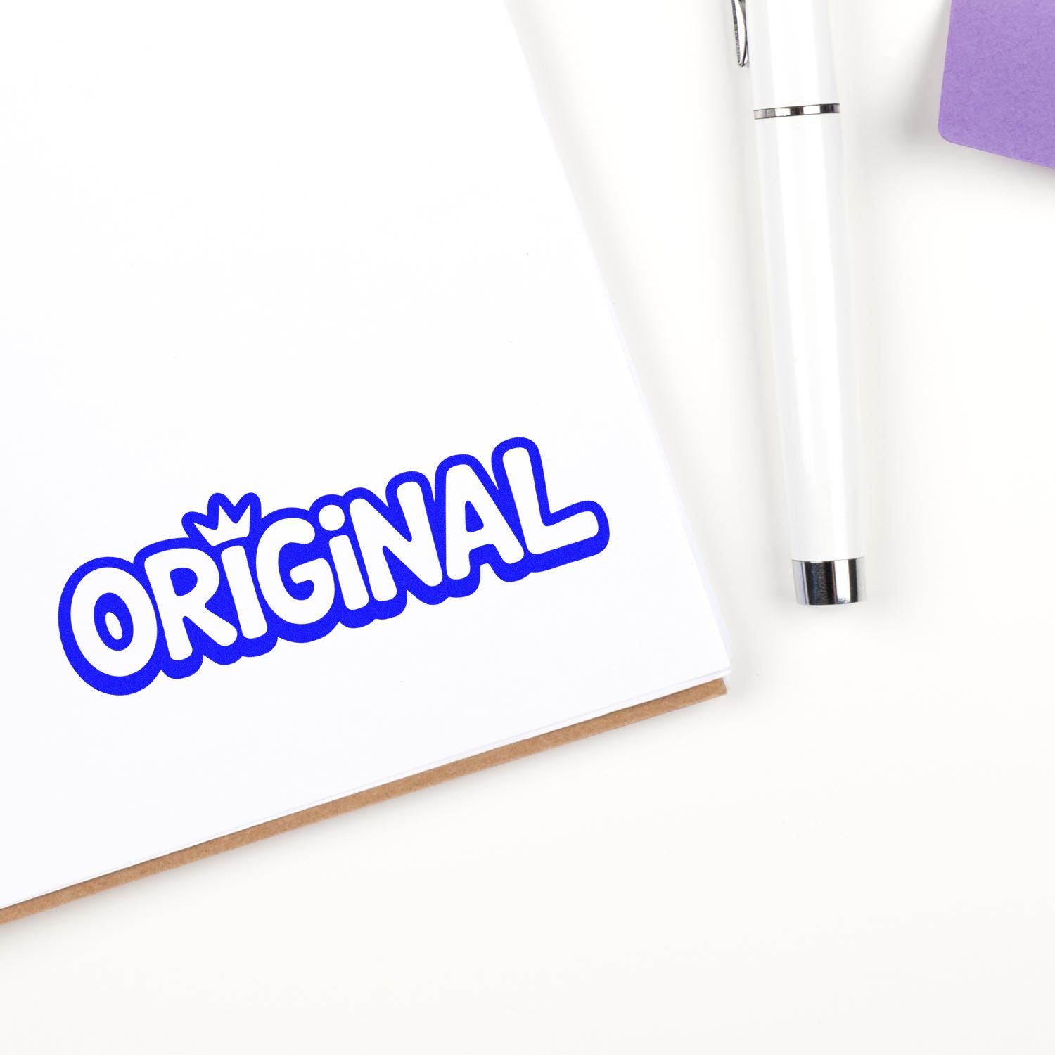 Blue ORIGINAL seal stamp on white paper beside a white pen, with a purple accent.