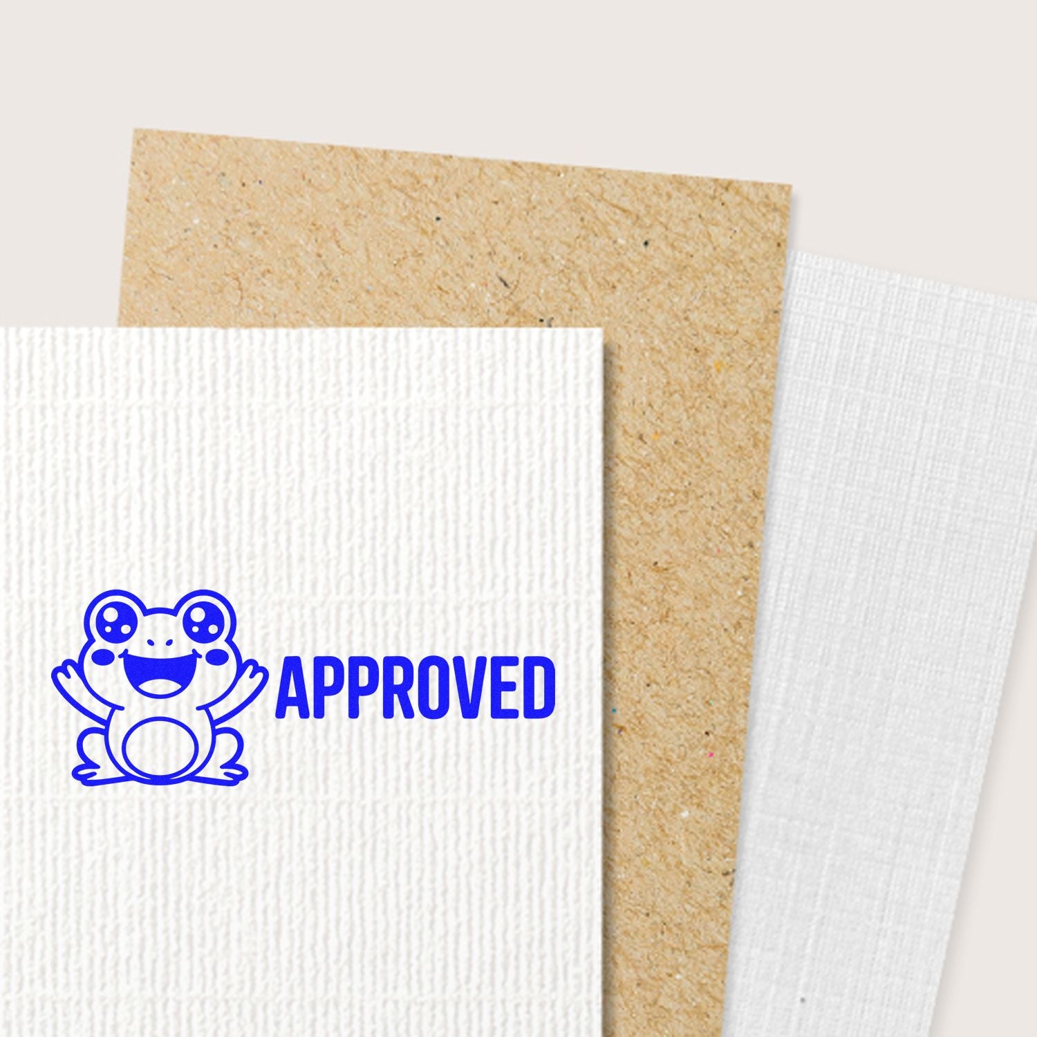 Blue frog APPROVED stamp on white textured cardstock, with tan and white seal paper sheets behind.