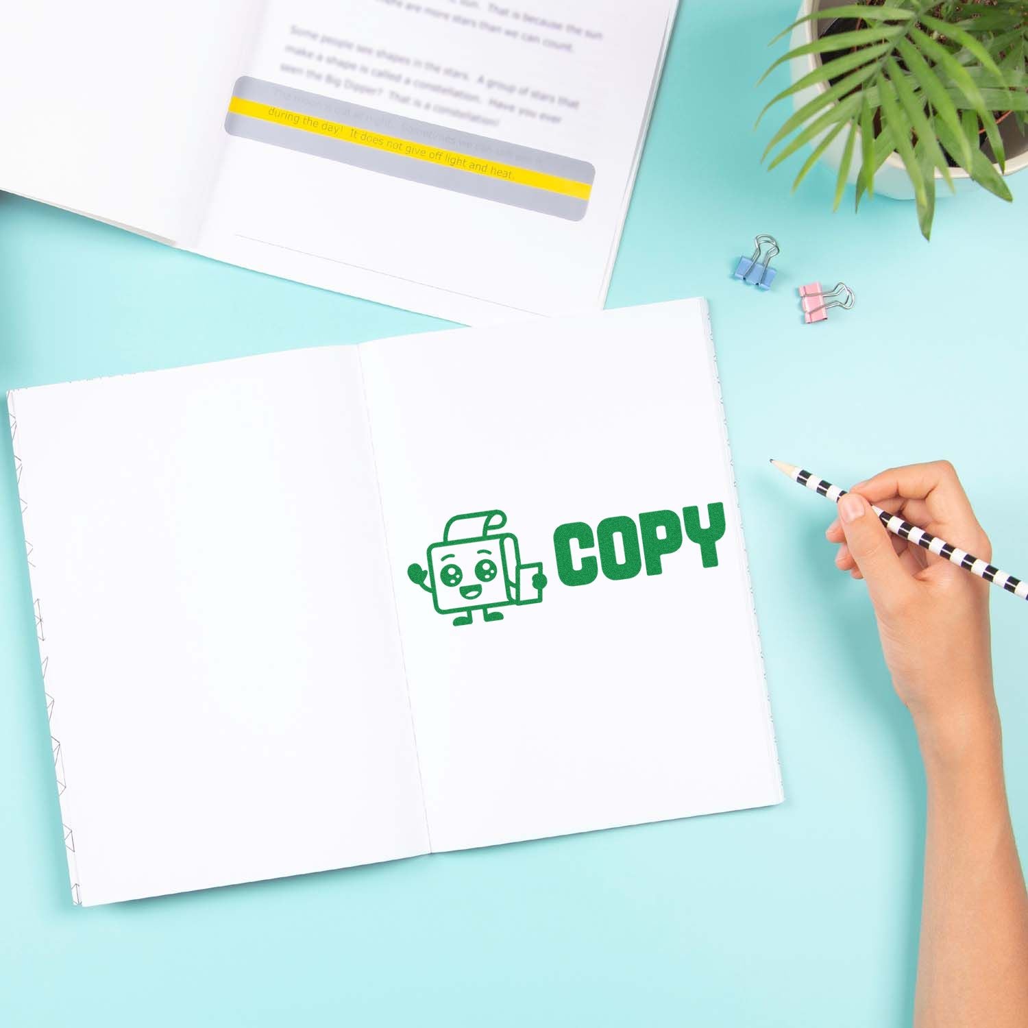 Green COPY stamp on open white notebook with a seal strip sample, striped pencil, and pastel blue desk.