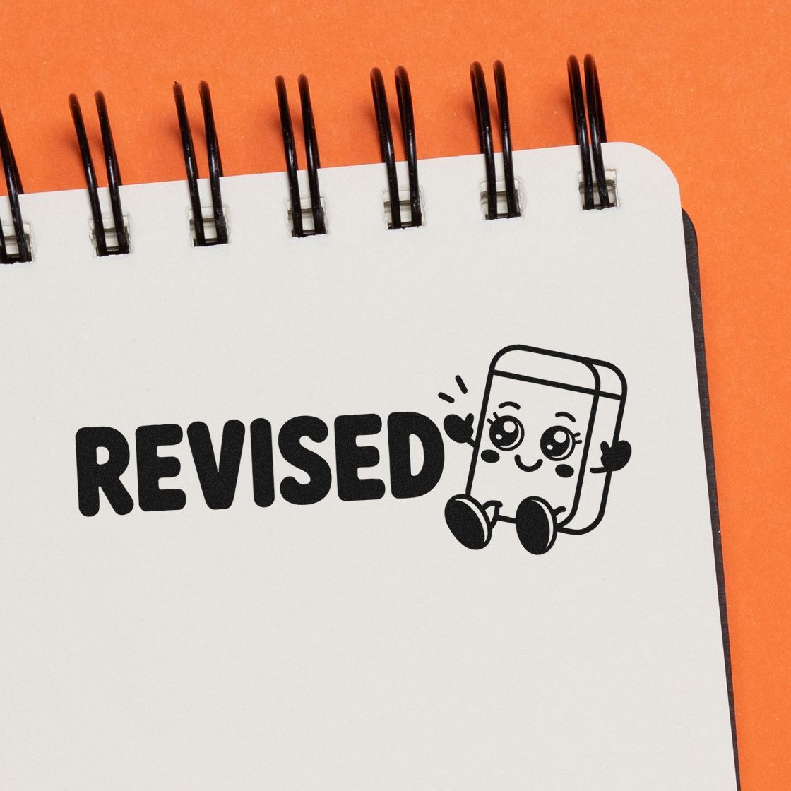 Black REVISED stamp and seal design with a cute mascot on a white spiral notebook, against an orange background.