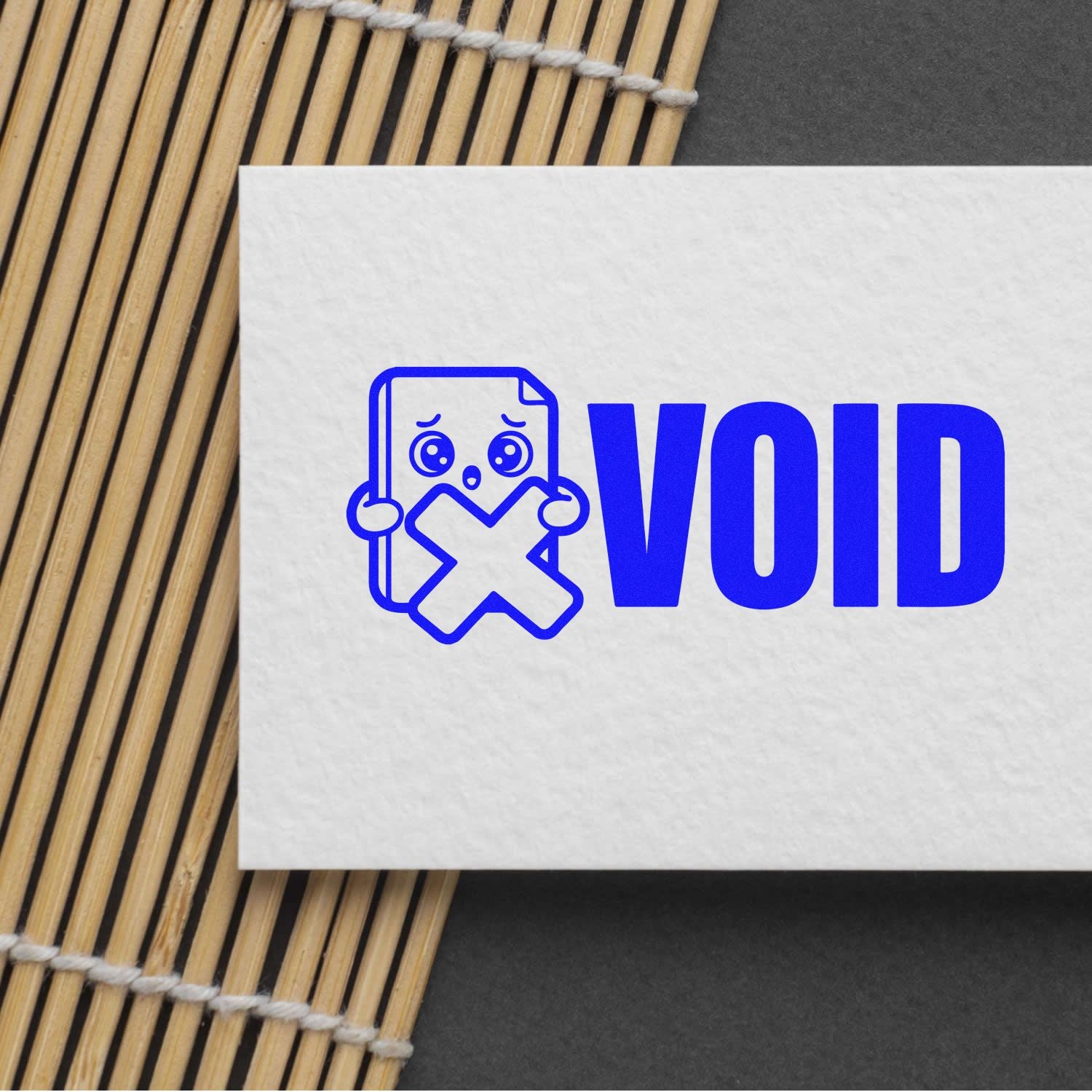Blue VOID stamp and seal on white card with sad document icon and X, set on a bamboo mat.