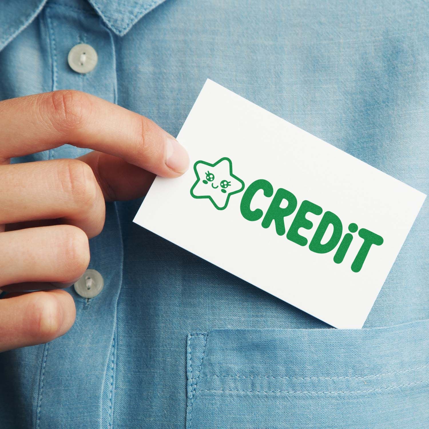 Hand holding white card with green CREDIT stamp logo and star seal on a blue shirt.