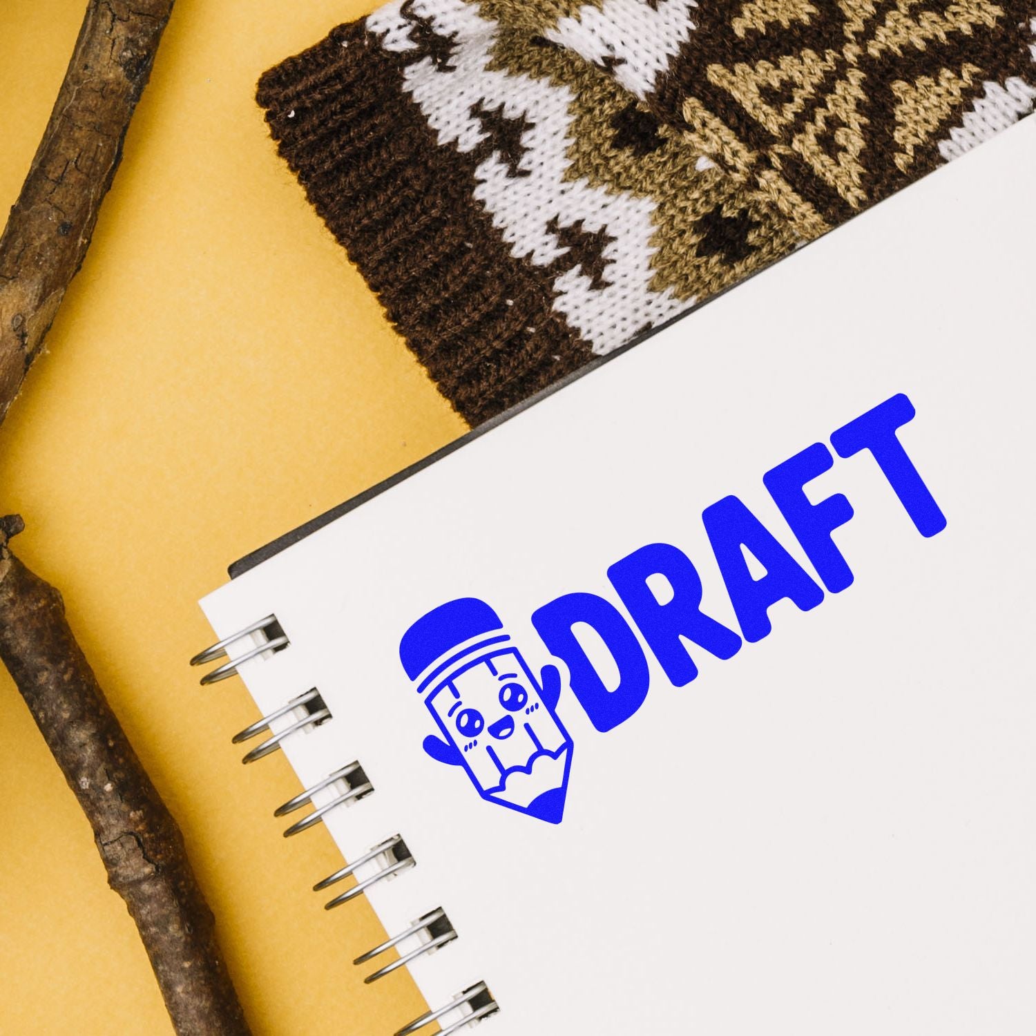Blue DRAFT stamp and pencil icon on white spiral notebook, alongside brown-and-white knit seal sample on yellow background.