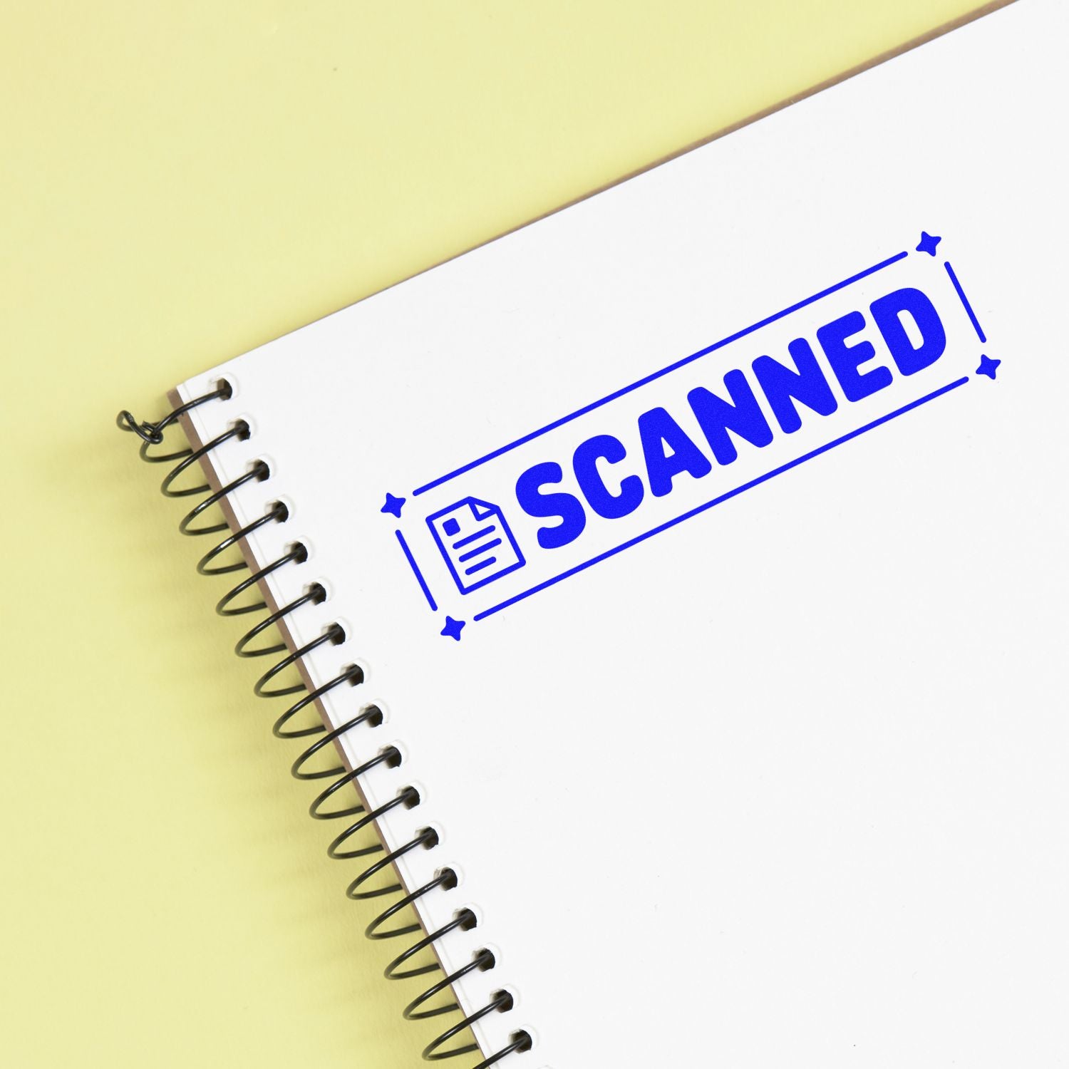 Spiral notebook with a blue SCANNED seal and document icon on a white page, set against a pale yellow background.