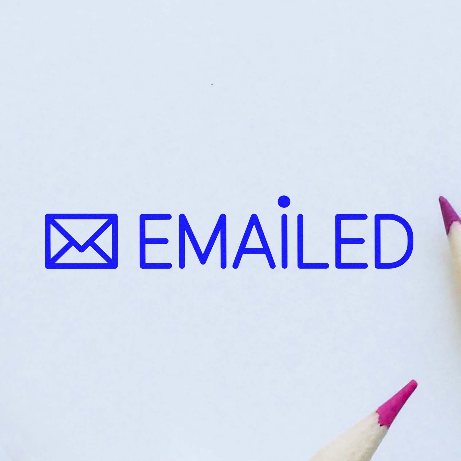 Blue self-inking emailed stamp with envelope icon on white paper, with pink pencil tips at right and bottom.