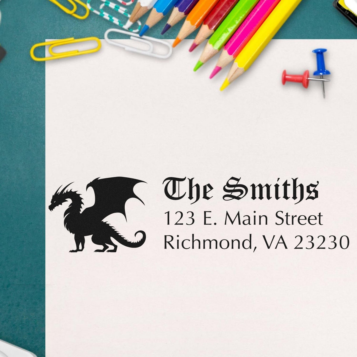 Custom stamp and seal card for The Smiths with black dragon logo, colorful pencils, paper clips, and pushpins on white paper.