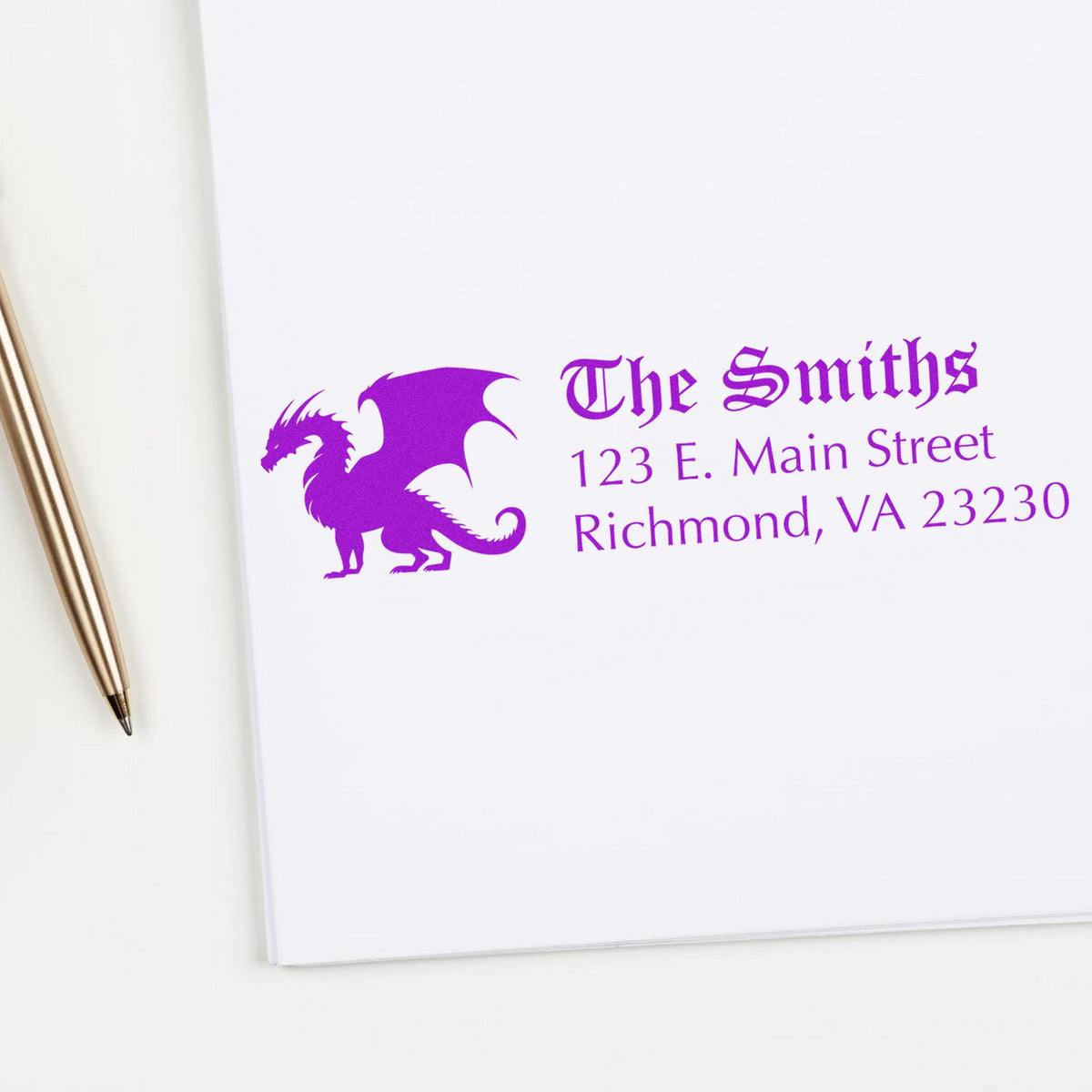 Purple custom stamp and seal with dragon logo, The Smiths address on white paper beside a gold pen.