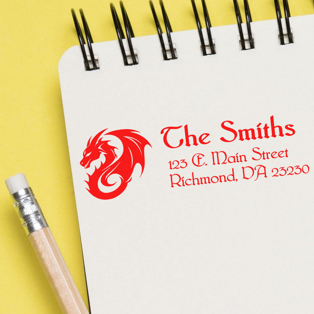 Custom red business stamp and seal on a white notebook, with dragon logo, name, and address on a yellow background.