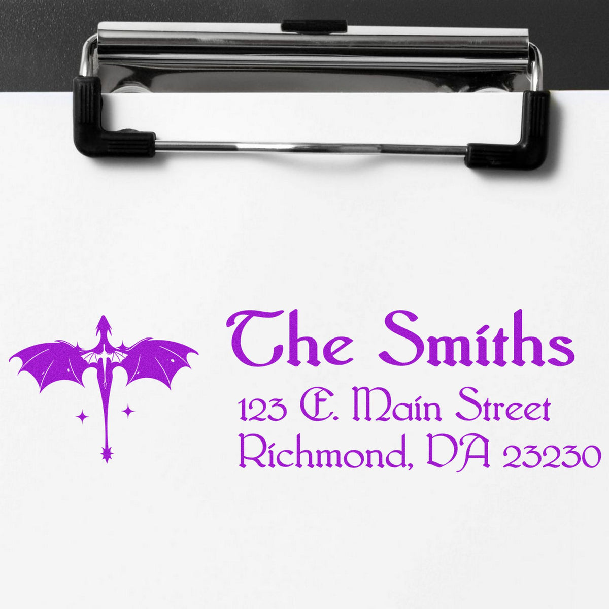 Chrome stamp and seal clip holding white paper with a purple bat logo and The Smiths address text.