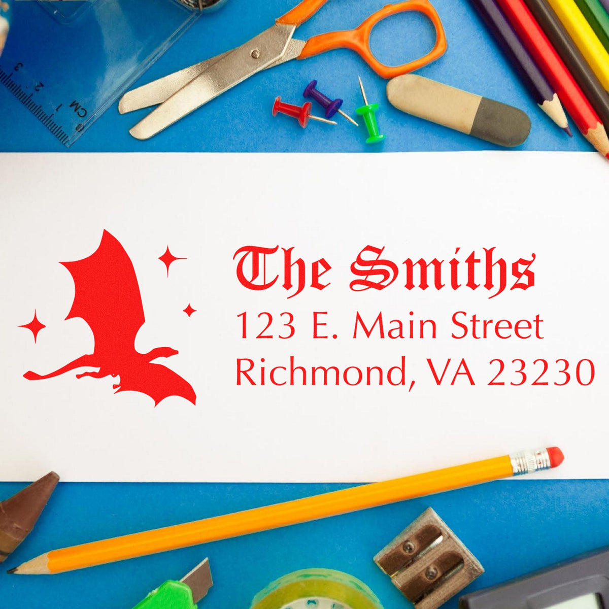 Red custom stamp and seal for The Smiths with bat logo and address on white card, surrounded by blue stationery.