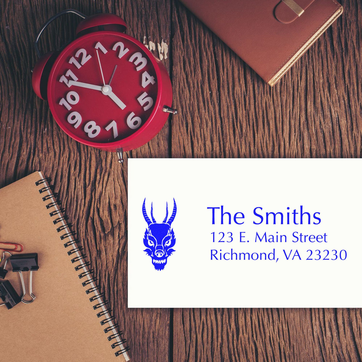Custom blue business seal/stamp for The Smiths with dragon logo and Richmond, VA address on a white card, on a wood desk.