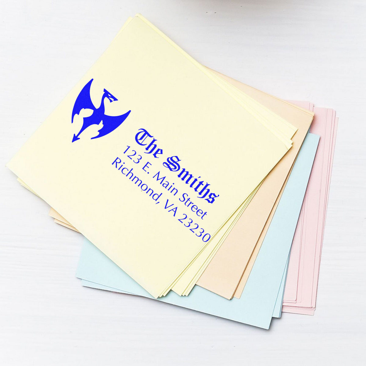 Pastel stamp and seal paper samples with blue dragon logo and Smiths address on stacked cream, blue, pink, and beige sheets.