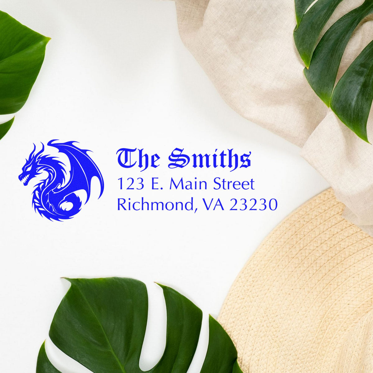 Blue dragon logo custom stamp seal for The Smiths with address on white background, framed by green leaves and beige fabric.