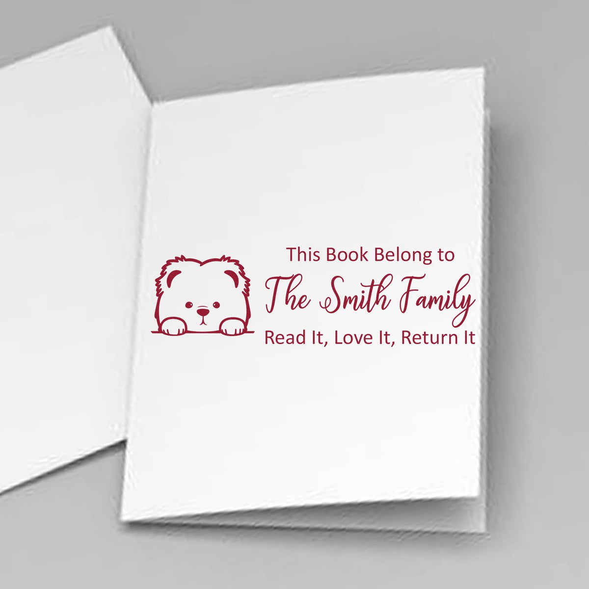 Burgundy custom book stamp with bear icon and This Book Belongs to The Smith Family on white paper.