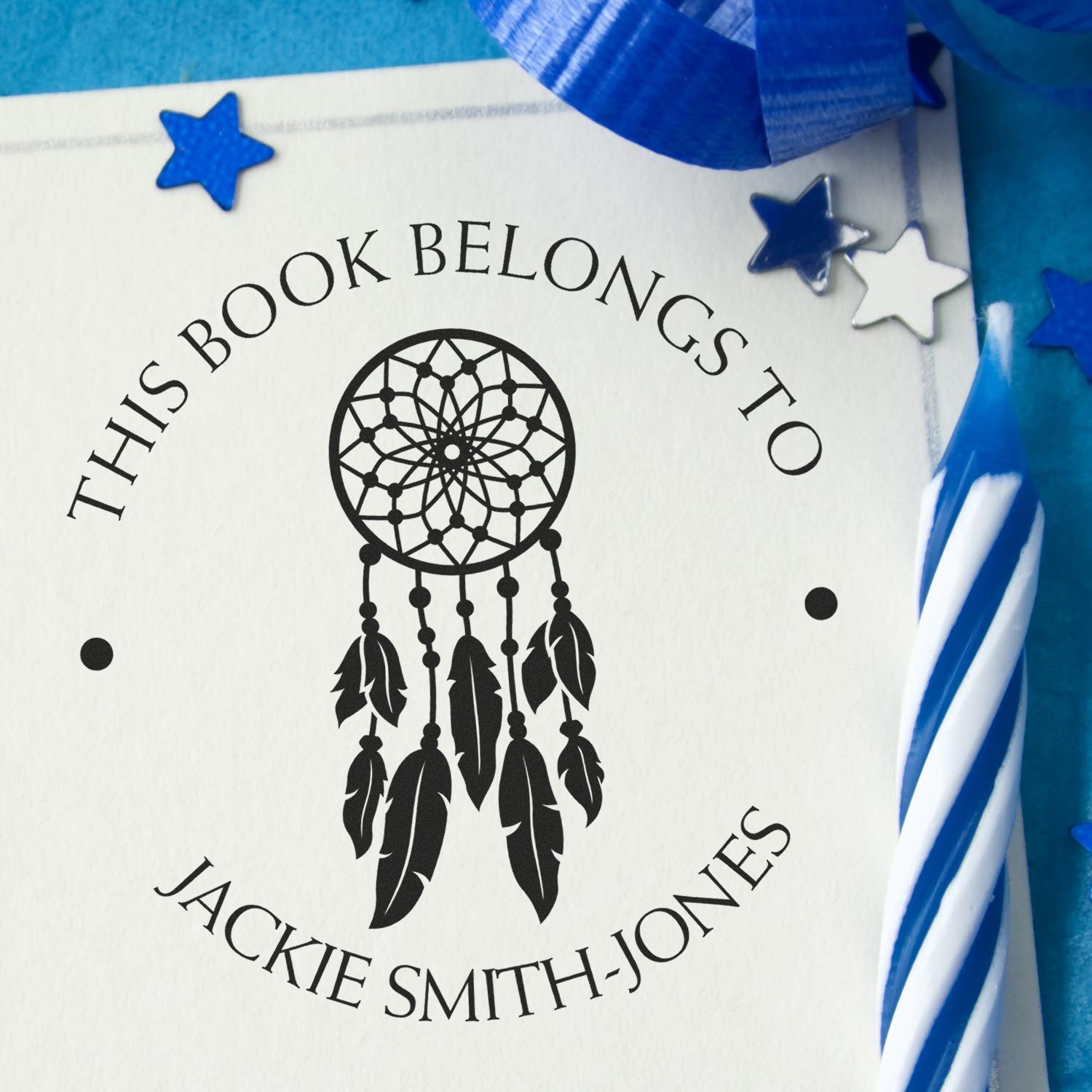 Black dreamcatcher book seal on white paper with blue ribbon and star accents, personalized This Book Belongs To Jackie Smith-Jones