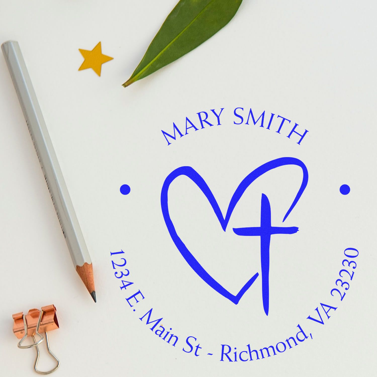 Blue custom stamp seal with heart and cross logo, Mary Smith, 1234 E. Main St., Richmond, VA, plus pencil and leaf.