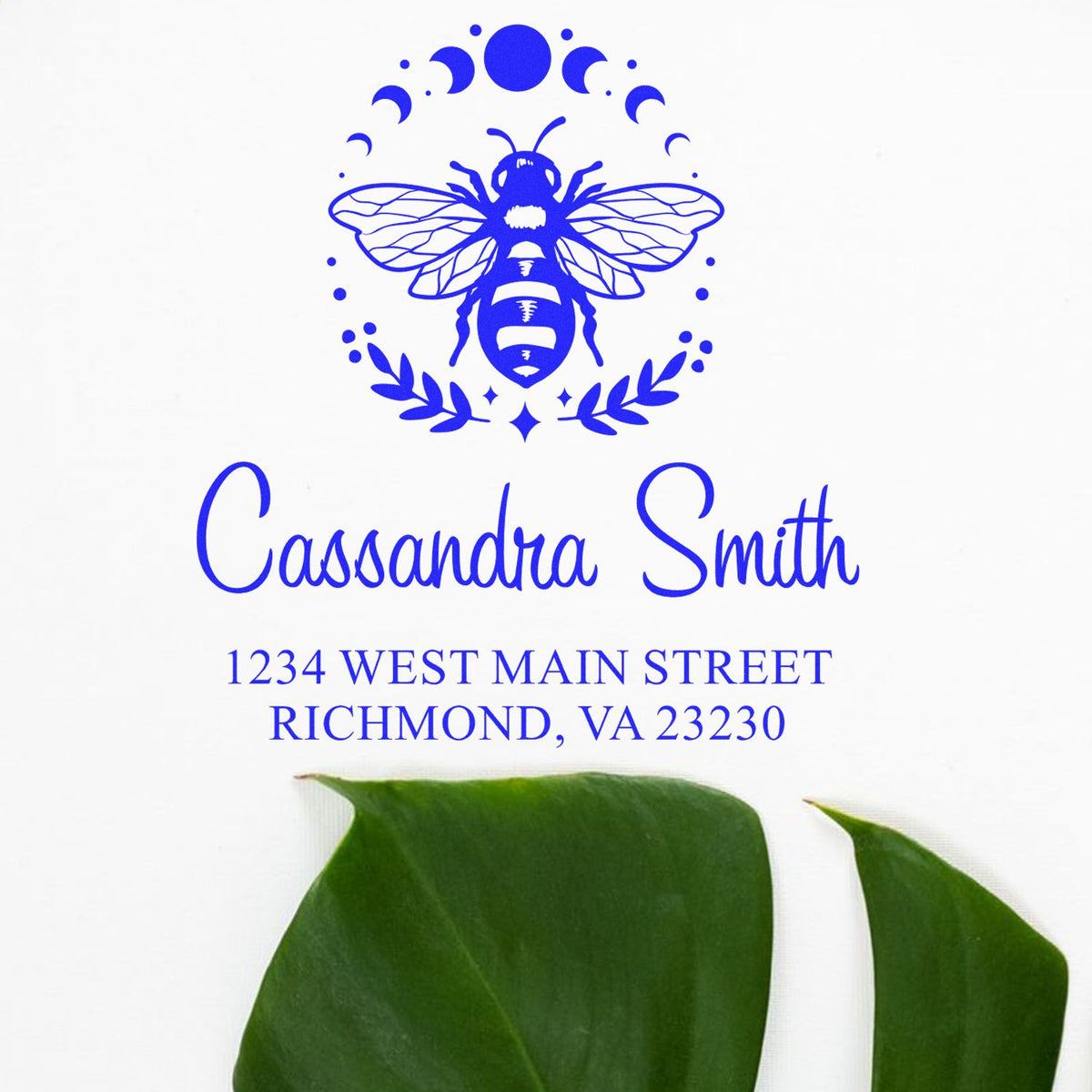 Blue custom stamp seal with bee emblem, Cassandra Smith name and Richmond, VA address, on white with green leaves.
