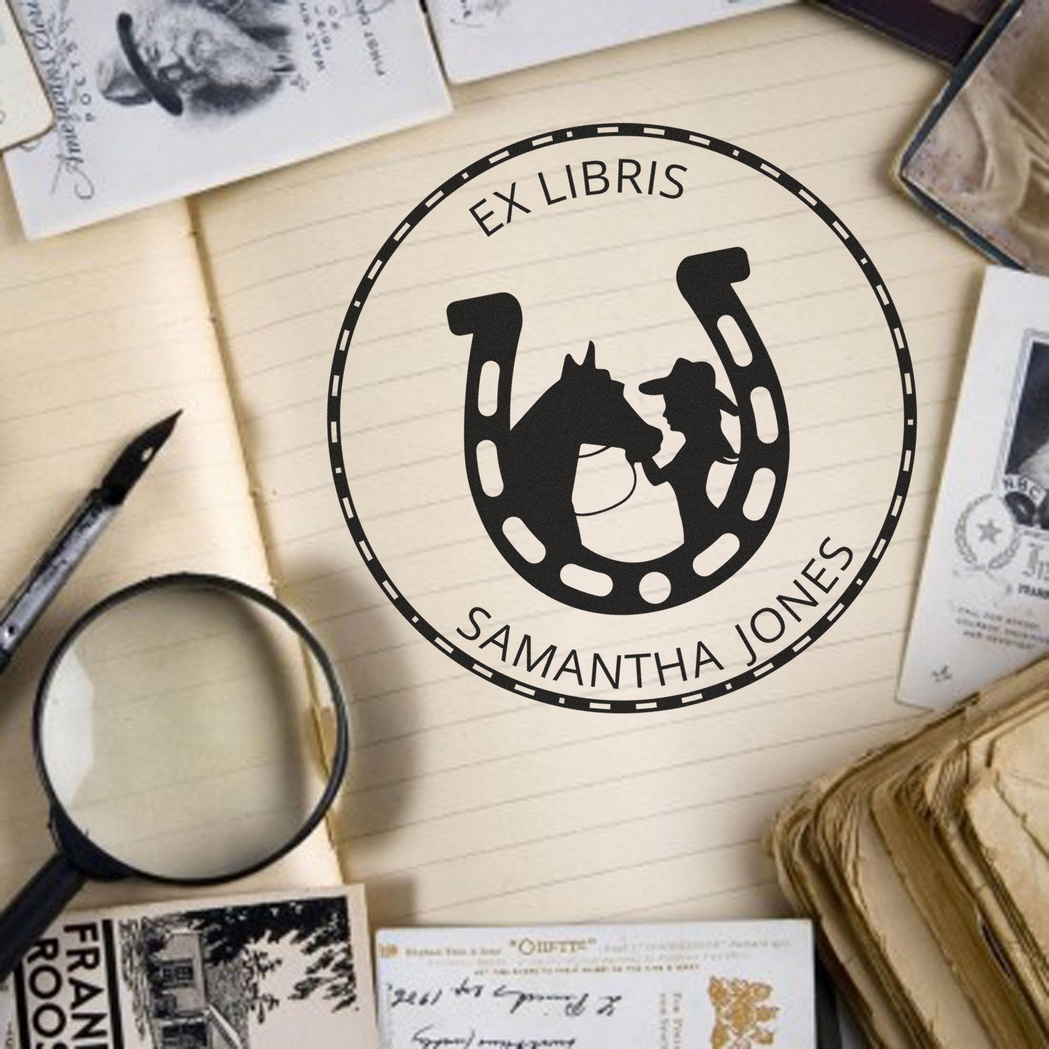 Black custom ex libris horseshoe stamp seal with horse and rider, Samantha Jones, on a cream notebook with stationery.