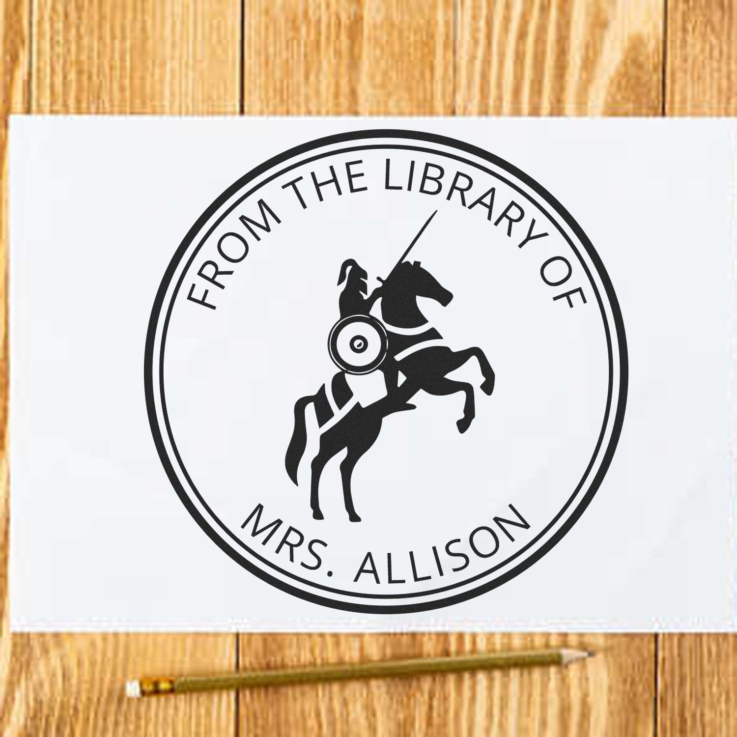 Black circular library stamp seal with horse and rider, reading From the Library of Mrs. Allison, on white paper over wood.
