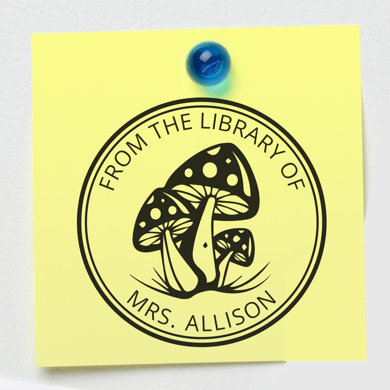 Yellow sticky note with black library stamp seal reading From the Library of Mrs. Allison, featuring mushrooms and a blue pushpin.