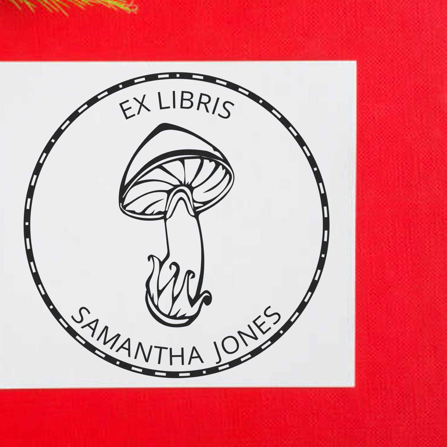 Black Ex Libris mushroom stamp seal with Samantha Jones text on a white square, set against a bright red background.
