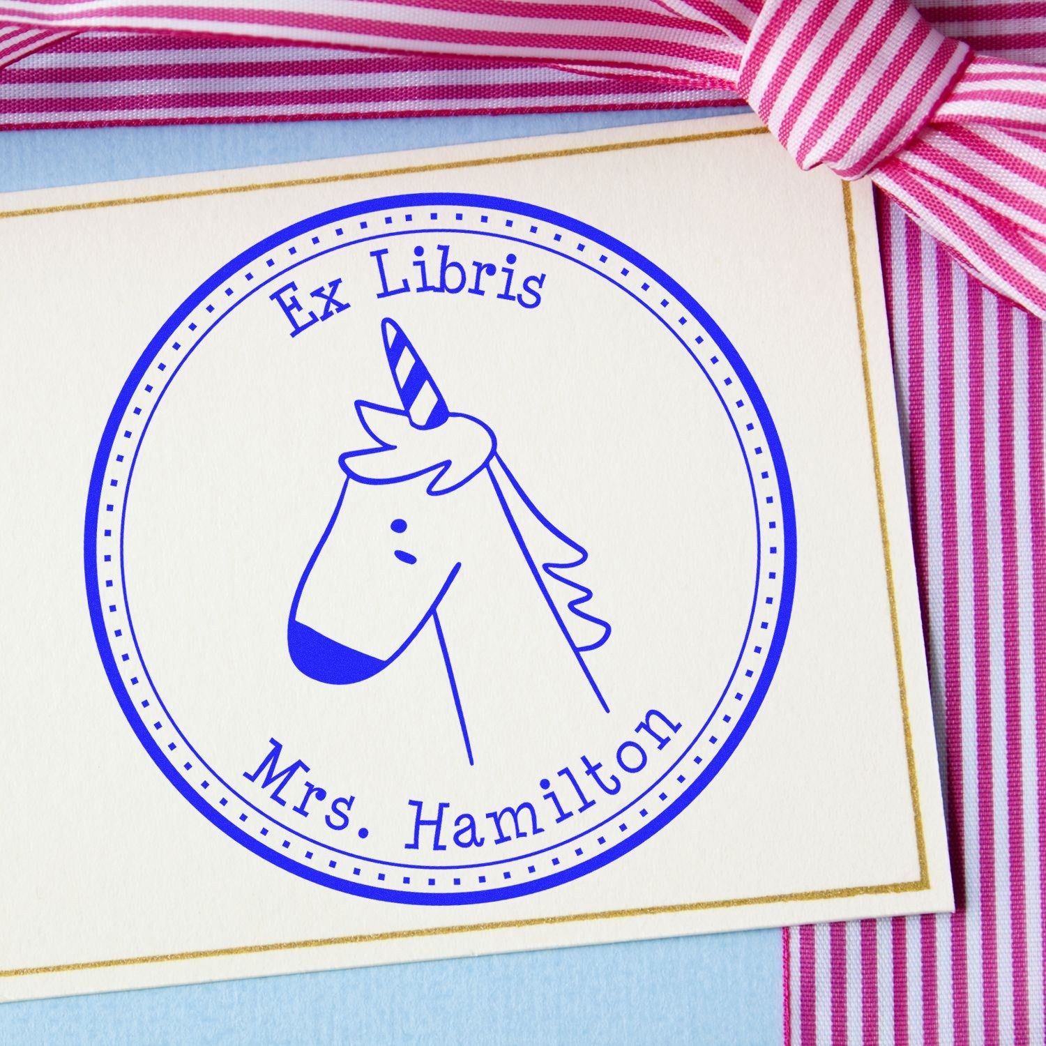 Slim Pre-Inked GlimmerGlide Cartoon Animal Custom Bookplate Template Stamp featuring a unicorn design with "Ex Libris" and "Mrs. Hamilton" text. Ideal for personalized return mail stamps, shown on a card with pink striped ribbon.