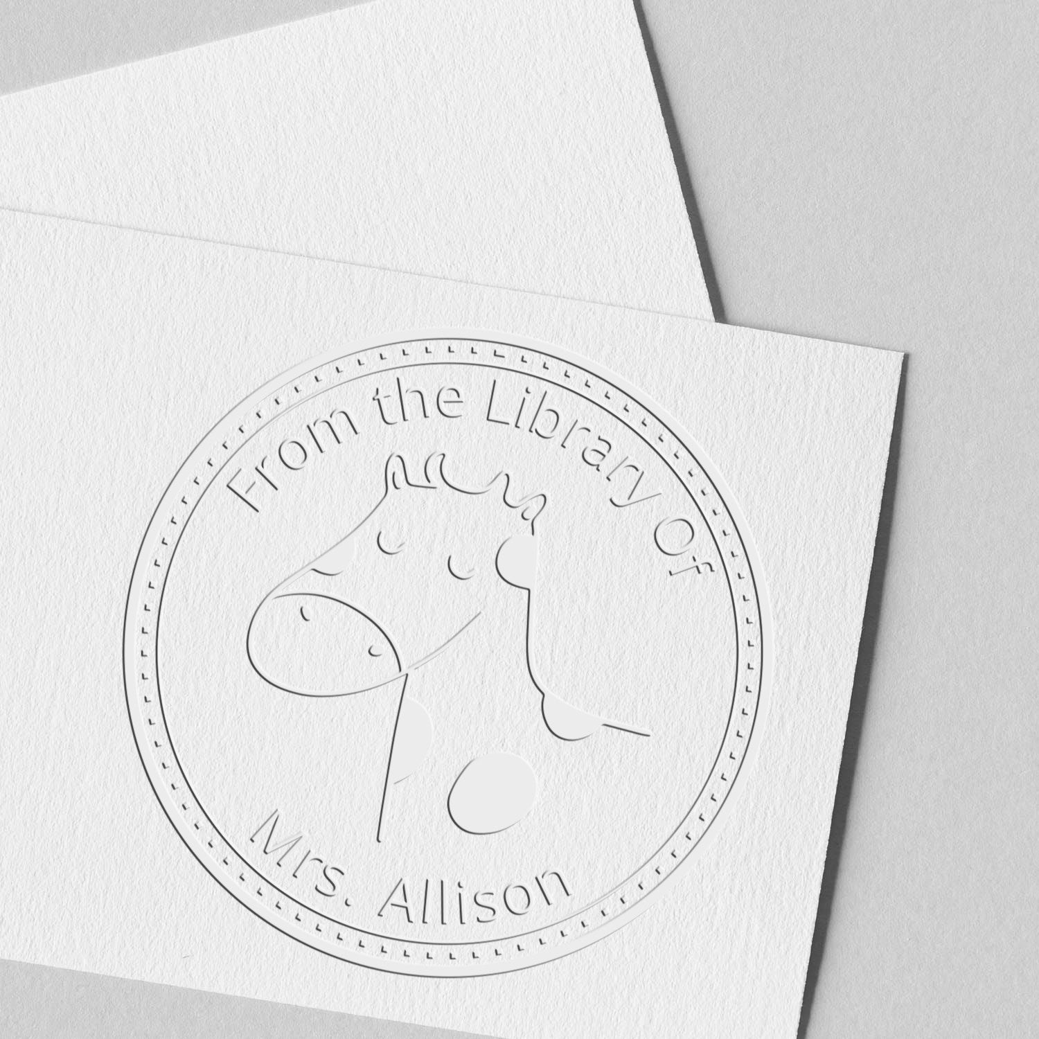 BoopSnoot cartoon animal design on a handheld personalized Ex Libris book seal, featuring a custom address stamp with the text "From the Library Of Mrs. Allison" embossed on white paper.