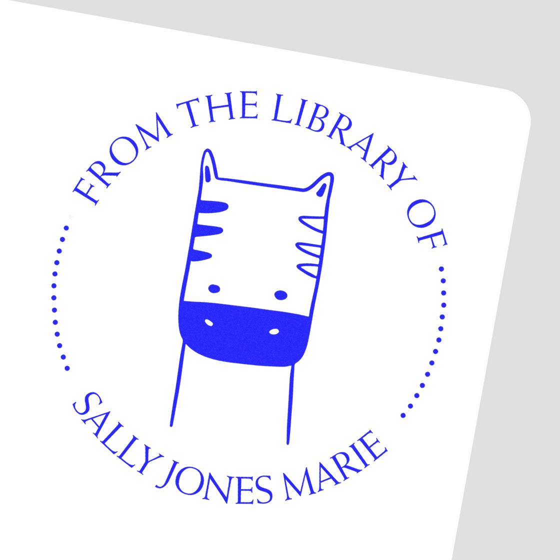 A Slim Pre-Inked PuzzlePounce Cartoon Animal Custom Bookplate Maker Stamp is shown on a white surface. The stamp features a cute cartoon animal with text From the Library of Sally Jones Marie. This customizable home stamp is ideal for personalizing books.