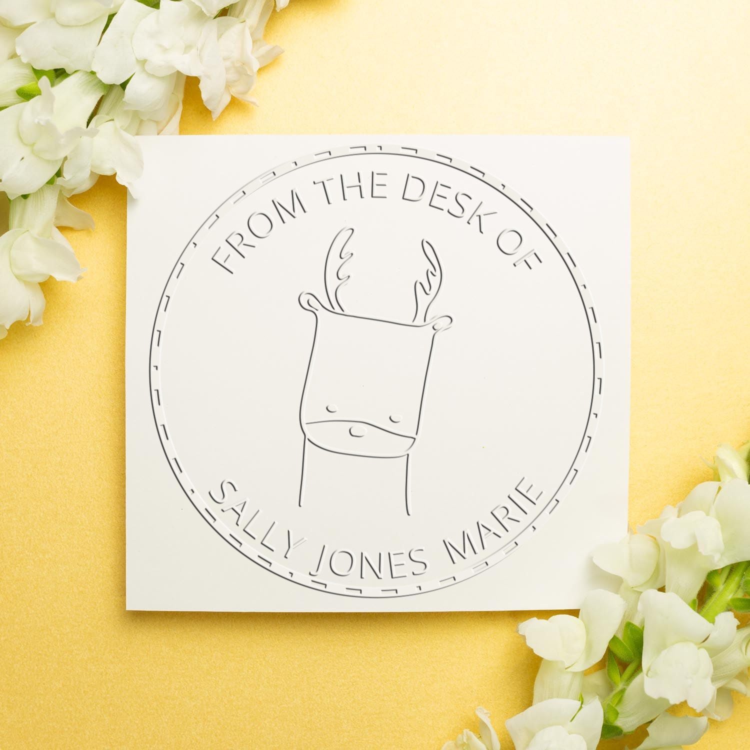 A custom-made book initial seal featuring a soft MerryMuzzle cartoon animal design is displayed on a white card with floral accents. The personalized new address stamper reads "From the Desk of Sally Jones Marie" in a circular layout.
