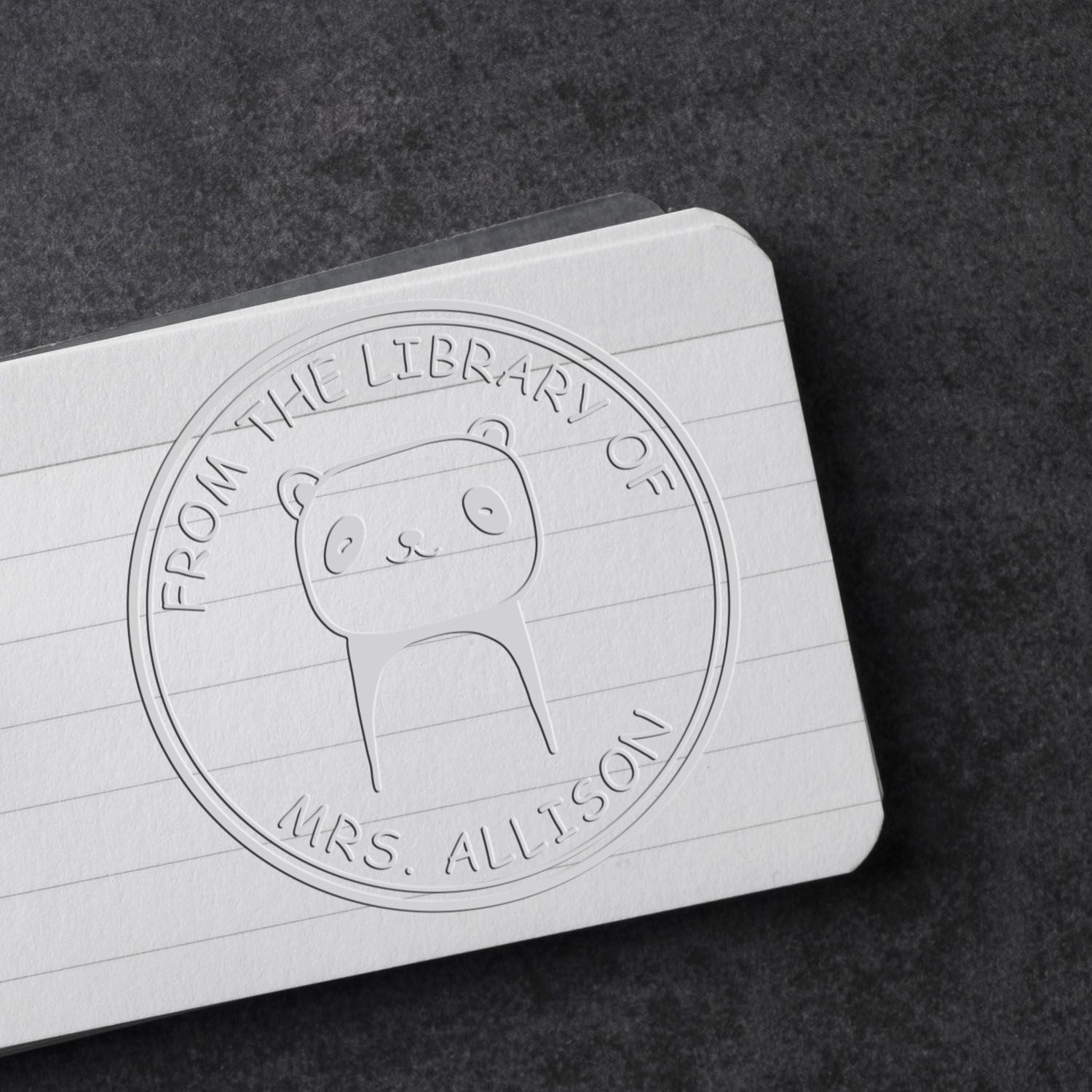 TumbleTuft cartoon animal embossing seal on a lined card, featuring a cute character. The text reads "From the Library of Mrs. Allison." This custom-made home stamper is handheld and personalized for library use.