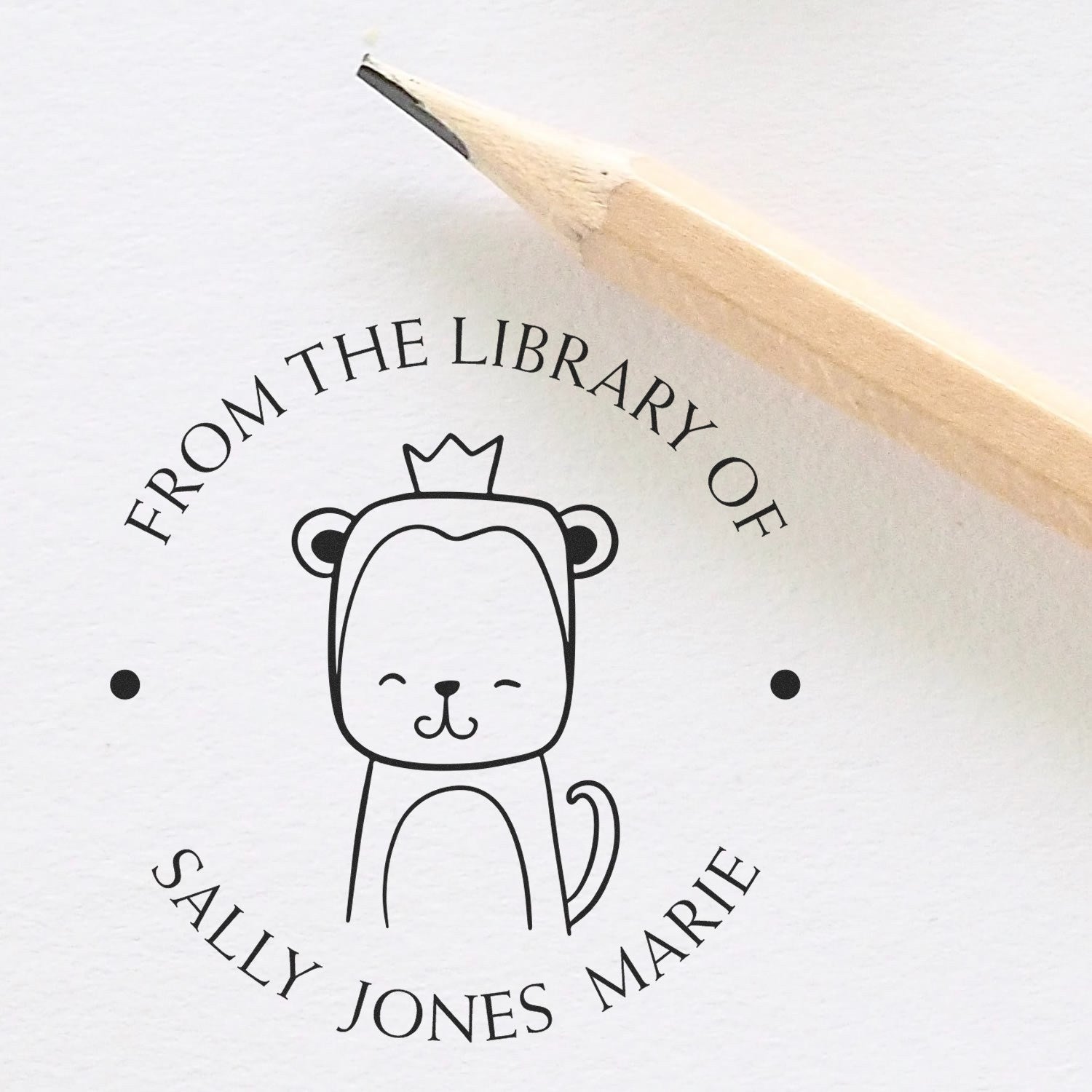 A Slim Pre-Inked ScribbleScrabble Cartoon Animal Custom Library Stamp featuring a crowned animal design with the text "From the Library of Sally Jones Marie" next to a pencil. Ideal for a Customized New Address Stamper.